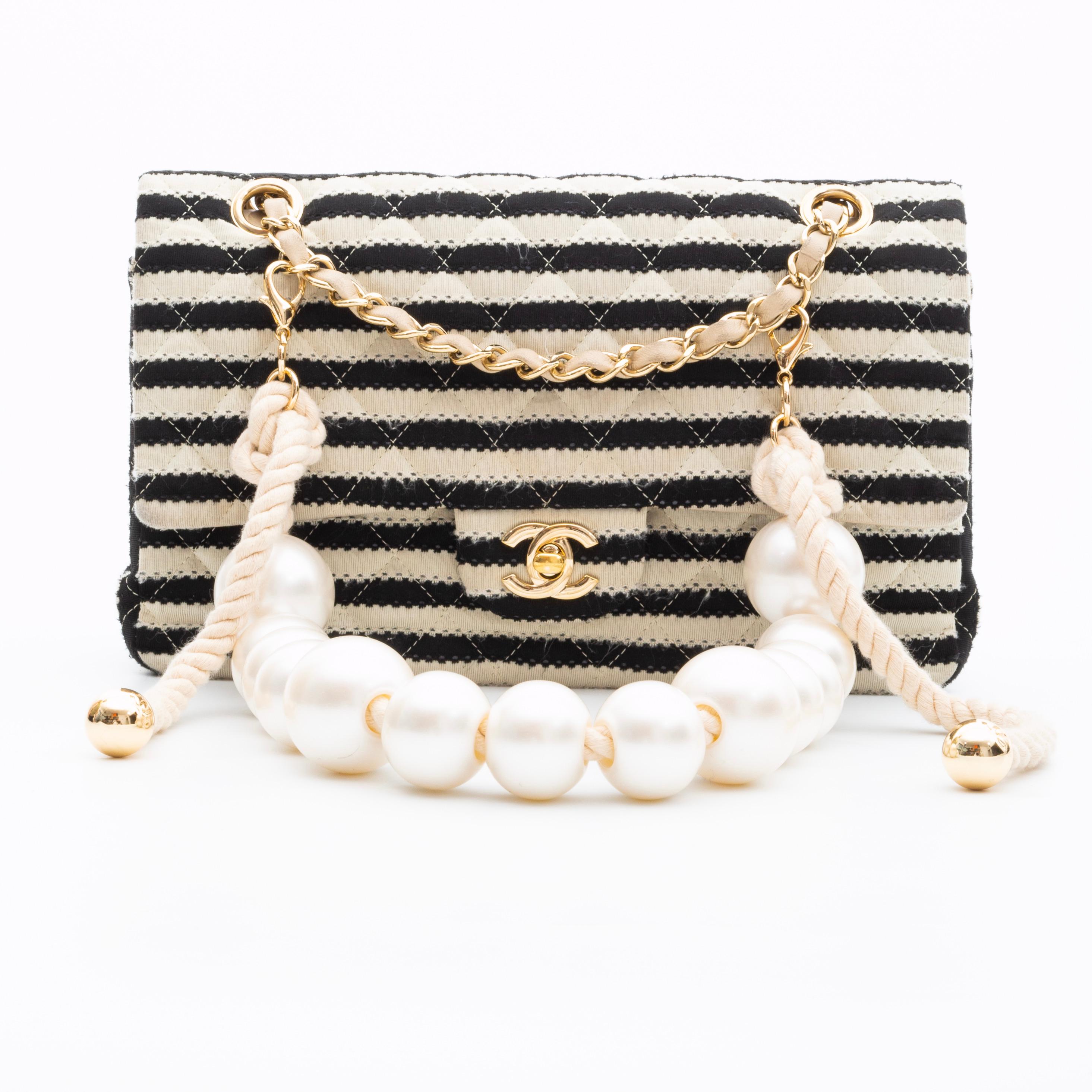 Note the strap was removed from another bag called Chanel By The Sea. Lobster clasp closure was added to be clipped on a bag.

COLOR/MATERIAL: Gold metal and faux pearl white
MEASURES: H 6.25” x L 10”
COMES WITH: Dust bag
CONDITION: Excellent -