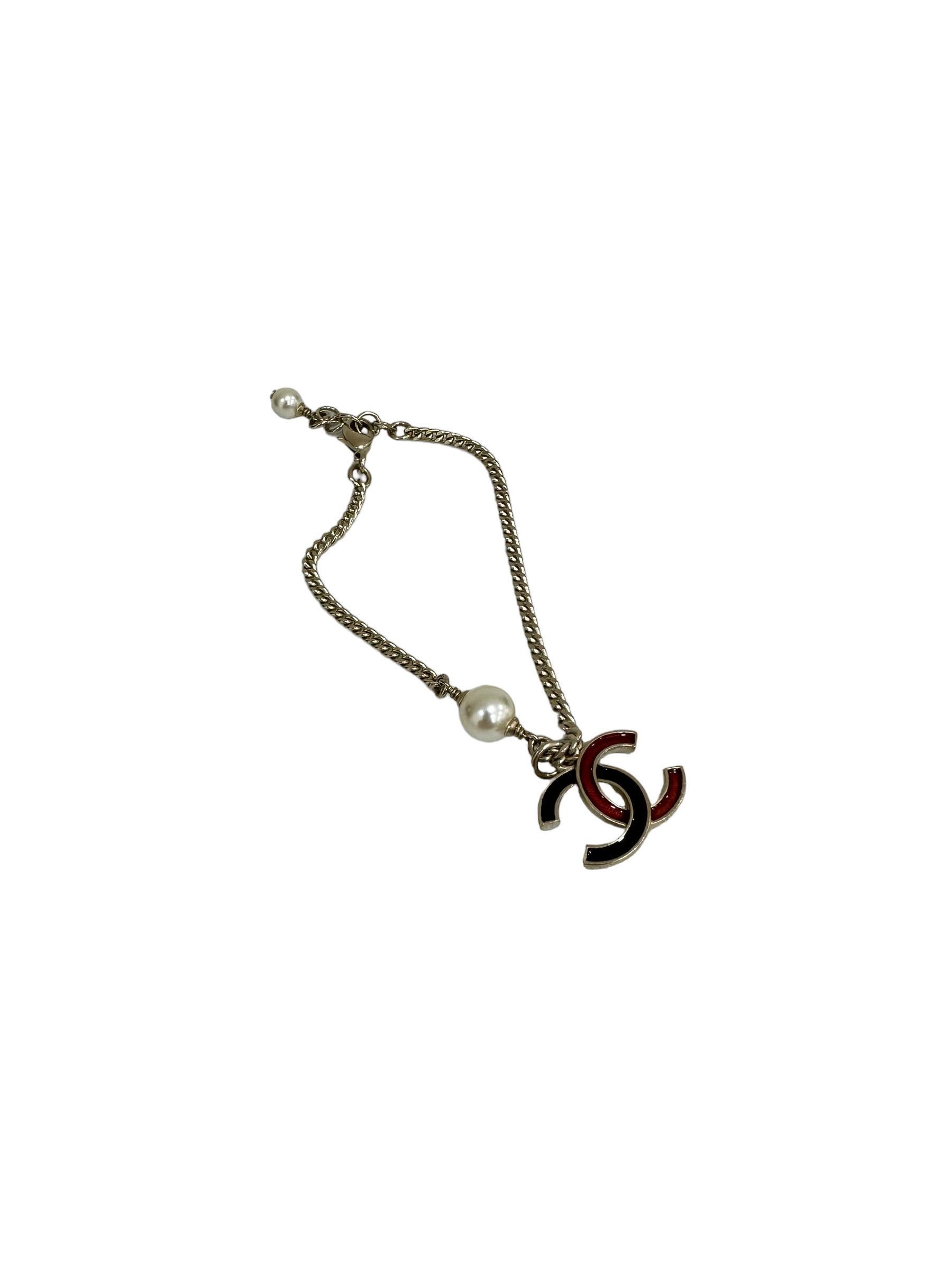 Bracciale firmato Chanel, realizzato in metallo dorato. Dotato di chiusura a gancio. Dotato di un piccolo ciondolo bicolore con logo CC. Sembra in condizioni perfette.

