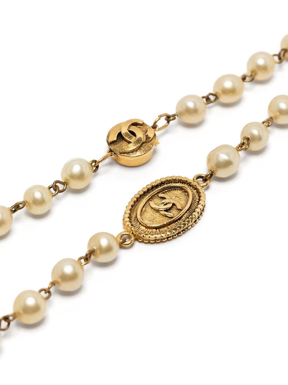Diese elegante, gebrauchte Halskette von Chanel aus antikgoldfarbenem Metall ist ein einzigartiges Stück, das jedem Outfit einen Hauch von klassischer Raffinesse verleiht. Die großformatigen Kunstperlenverzierungen und die ineinandergreifenden