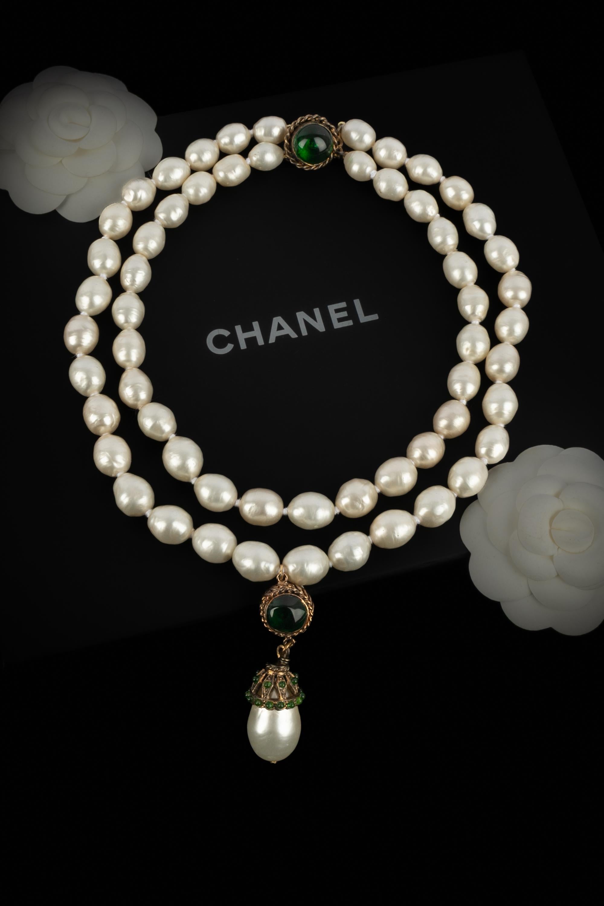 CHANEL - (Made in France) Zweireihige Trachtenperlenkette mit einem Medaillon, in dessen Mitte ein Cabochon aus Glaspaste sitzt. Schmuckstücke aus den frühen 1980er Jahren.

Bedingung:
Sehr guter Zustand

Abmessungen:
Länge der kürzeren Reihe: 42