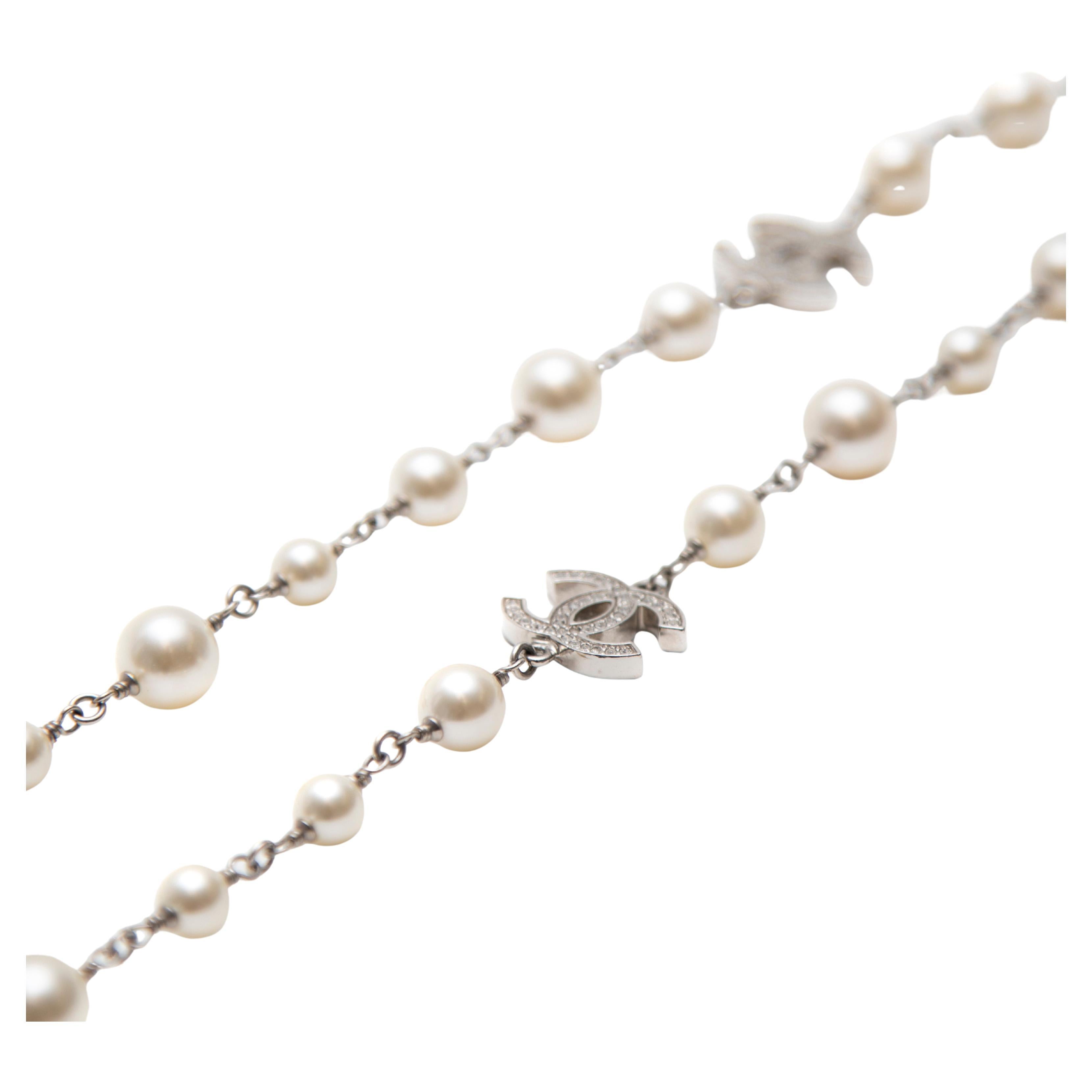 The Chanel Pearl Necklace is a stunning accessory designed by Karl Lagerfeld, blending timeless elegance with contemporary flair. This exquisite piece features a classic string of pearls in silver-toned metal, adorned with striking Strass crystal CC