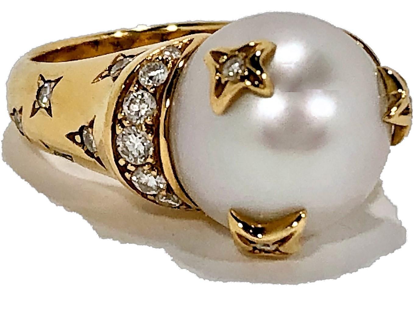 Made by Chanel in 18K yellow gold with one center 12mm 
cultured pearl covered with three diamond and gold stars. 
The ring has diamond shoulders directly underneath the
pearl as well as 12 diamonds set in star patterns along the
top side of the