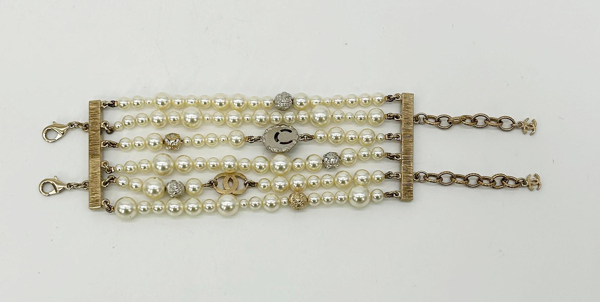 Chanel Pearl Multi Strand Charm Bracelet in excellent condition. Fabulous 6 strands of various size pearls with gold and silver metal beads, rhinestone metal beads, gold rhinestone CC logo charm, and gold/silver moon charm with resin planet inside.