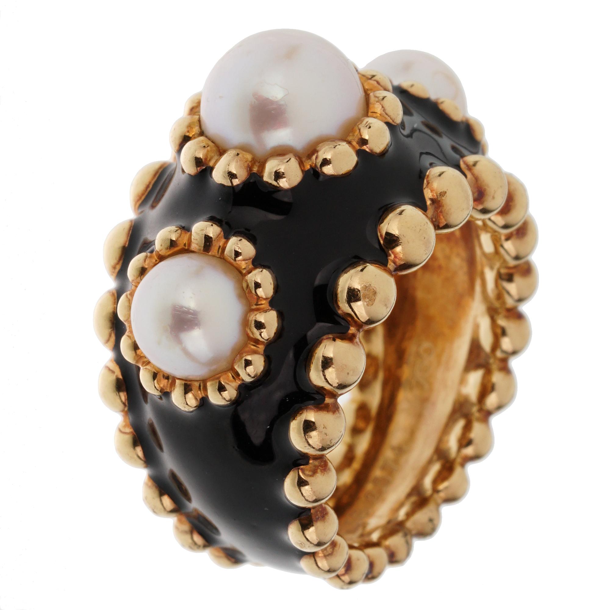 A lovely authentic Chanel ring showcasing 3 pearls each with a beaded row encased with black enamel in 18k yellow gold. The ring measures a size 5 3/4