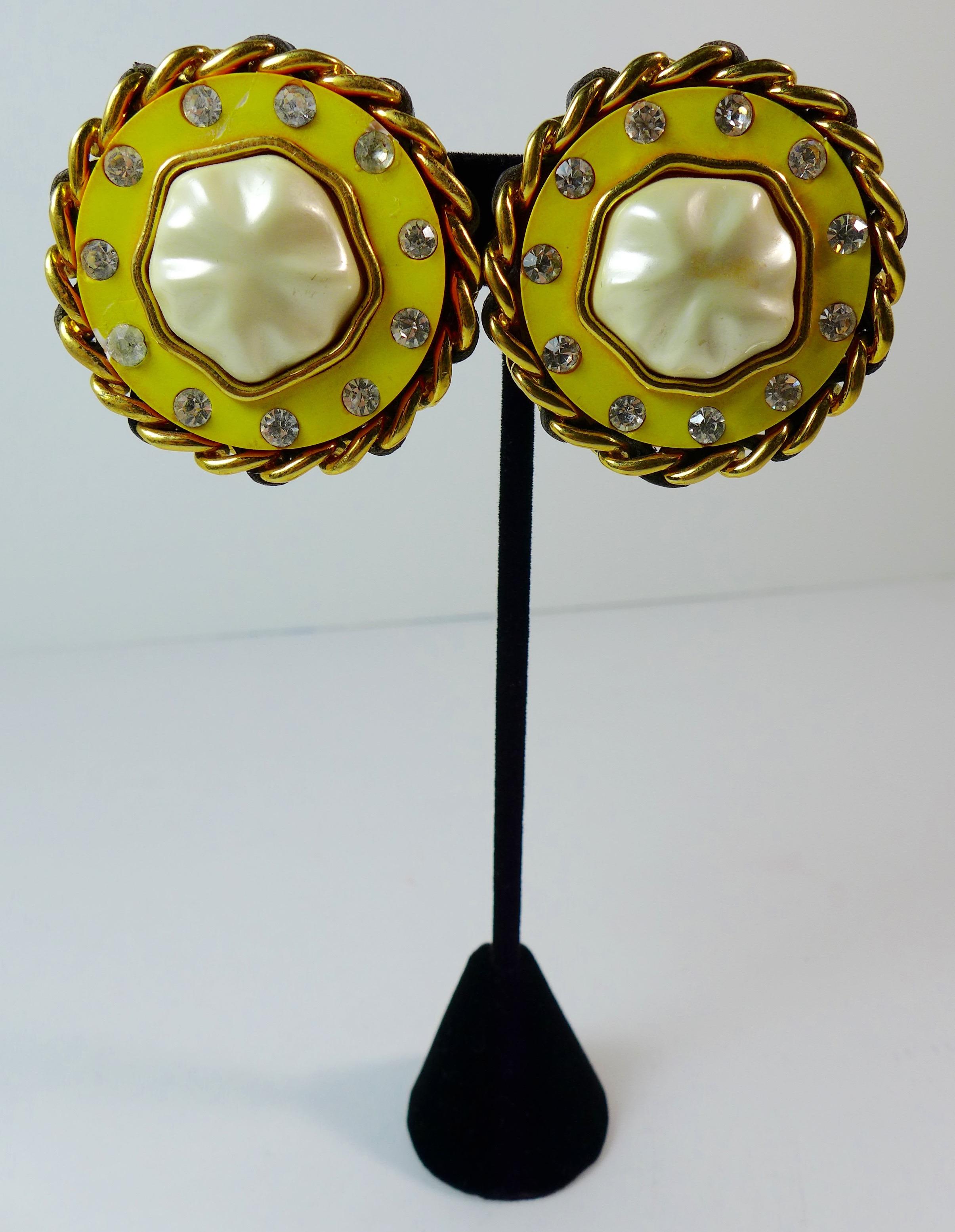 These Chanel clip on earrings feature a pearl center, yellow enamel with rhinestones, and a gold chain trim. Made in France. 