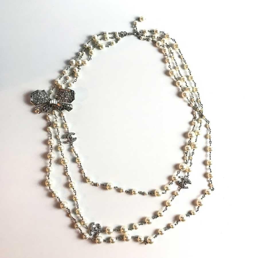 The necklace represents three rows of mother-of-pearl beads, with rhinestone CC emblems. The necklace sports a beautiful bow tie composed of rhinestones of different sizes. The bowtie has a hook, allowing to wedge well to your clothes.
The necklace