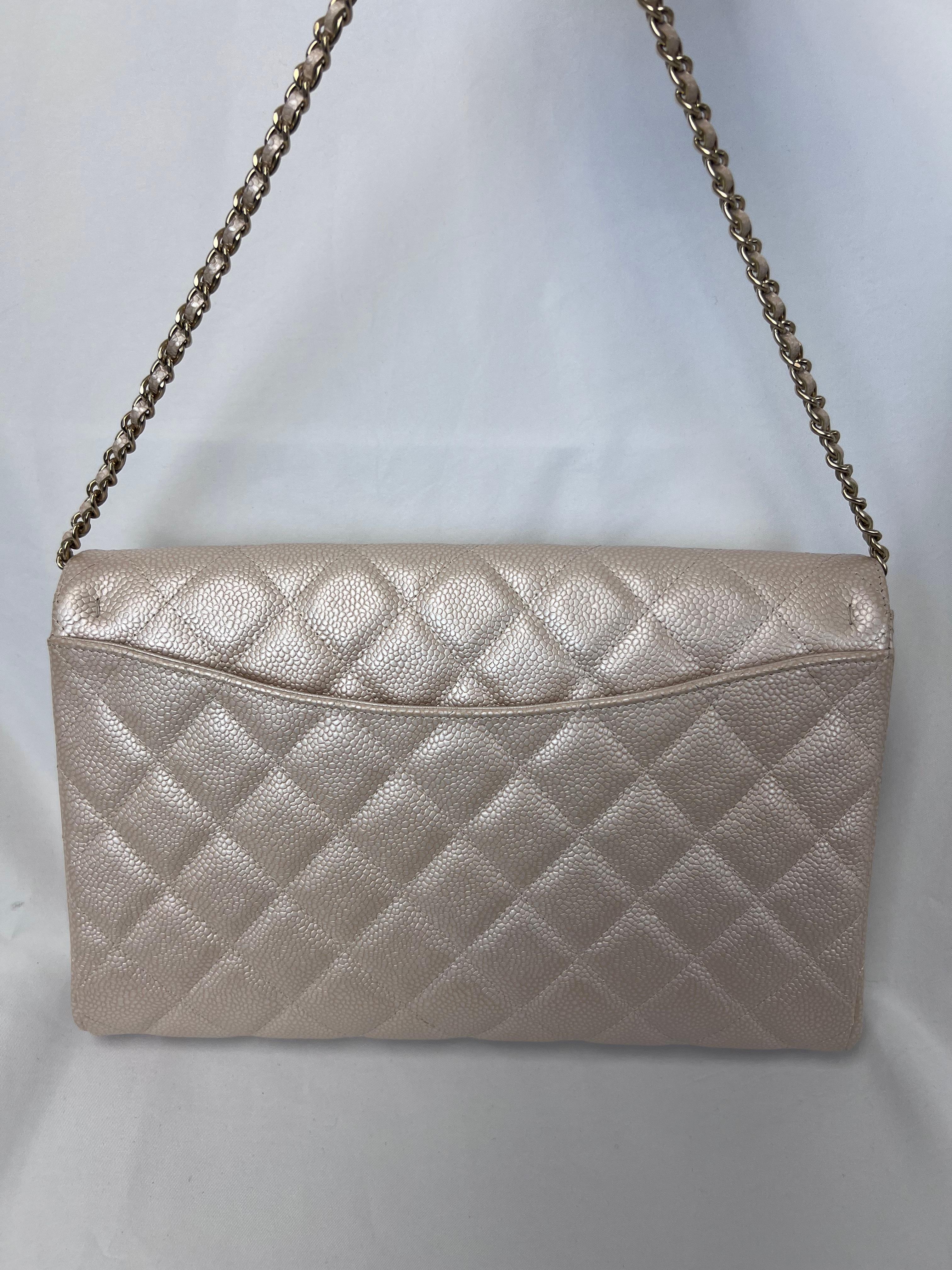 La pochette matelassée en caviar nacré de Chanel est un exemple exquis d'élégance intemporelle. Confectionné dans un luxueux cuir caviar nacré beige clair, ce sac présente le matelassage en losange emblématique et la fermeture à verrou tournant CC