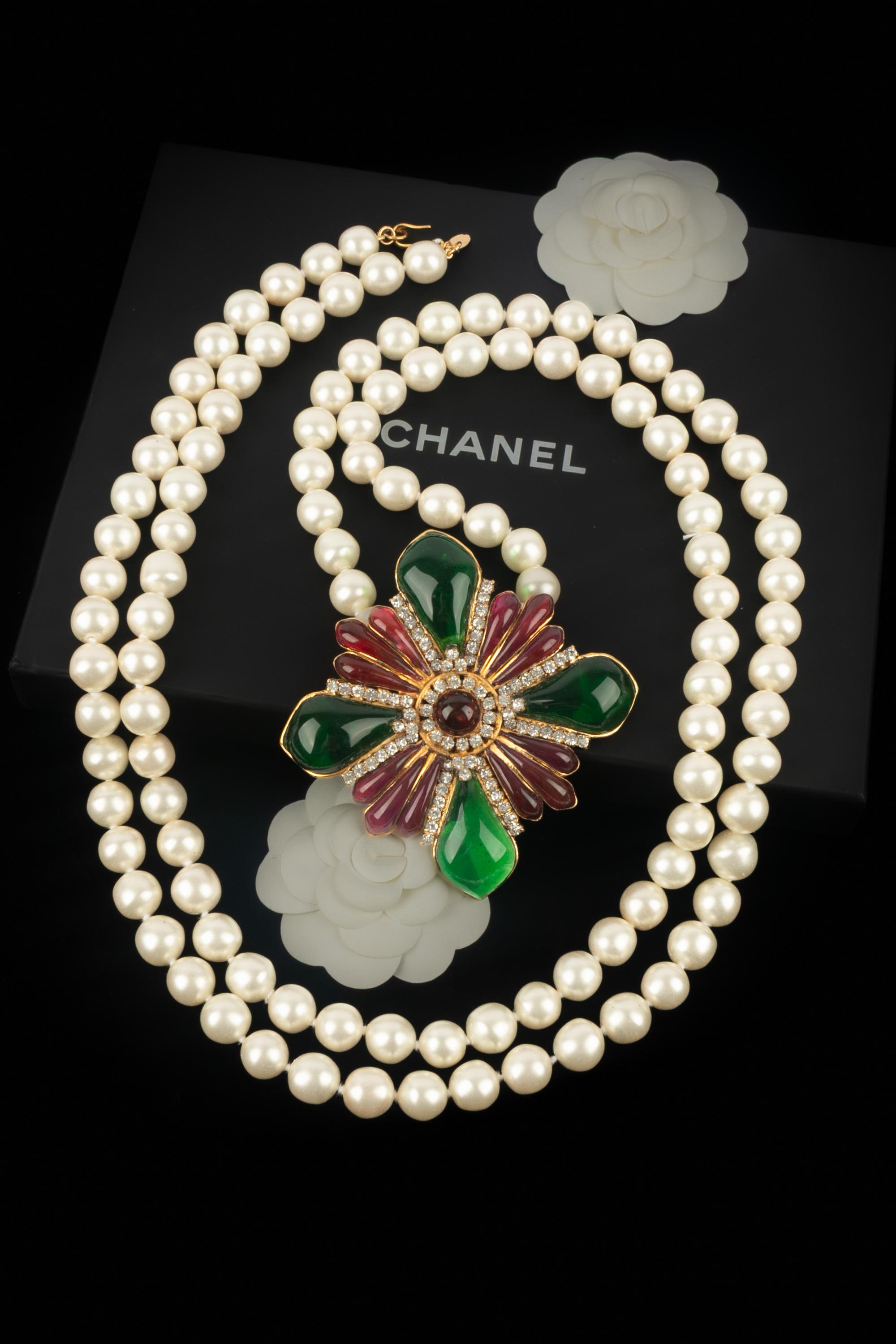 CHANEL - (Fabricado en Francia) Collar largo de perlas de fantasía con un colgante de metal dorado adornado con brillantes y pasta de vidrio verde y roja.

Estado:
Muy buen estado

Dimensiones:
Longitud: 180 cm - Colgante 11 cm x 11 cm

SKU:CB227