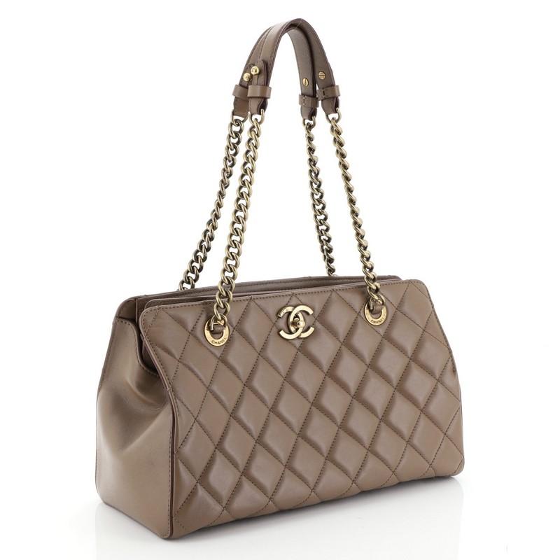 This Chanel Perfect Edge Tote Quilted Leather Small, crafted from brown quilted leather, features dual chain handles with leather shoulder pads and aged gold-tone hardware. Its CC turn-lock closure opens to a red fabric interior with zip and slip