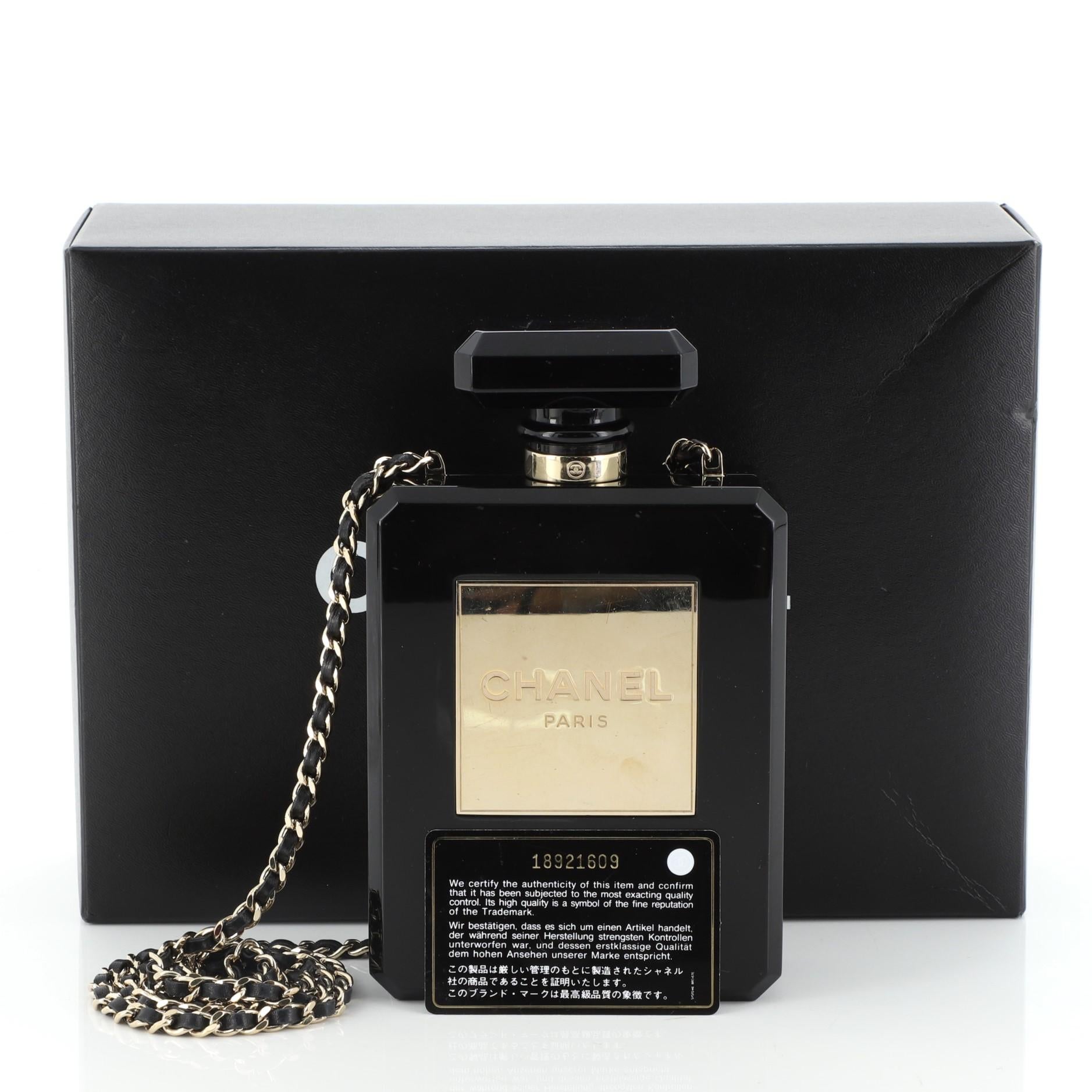 This Chanel Perfume Bottle Minaudiere Plexiglass, crafted from black plexiglass, features woven-in leather chain strap, Chanel Paris logo at front and gold-tone hardware. Its press-lock closure opens to a black leather interior. Hologram sticker