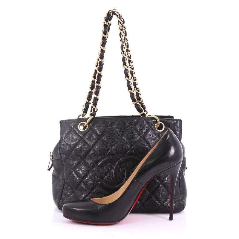 This Chanel Petite Timeless Tote Quilted Caviar, crafted from black quilted caviar leather, features woven-in leather chain straps, two exterior compartments, and gold-tone hardware. Its zip closure opens to a black fabric interior with side zip and