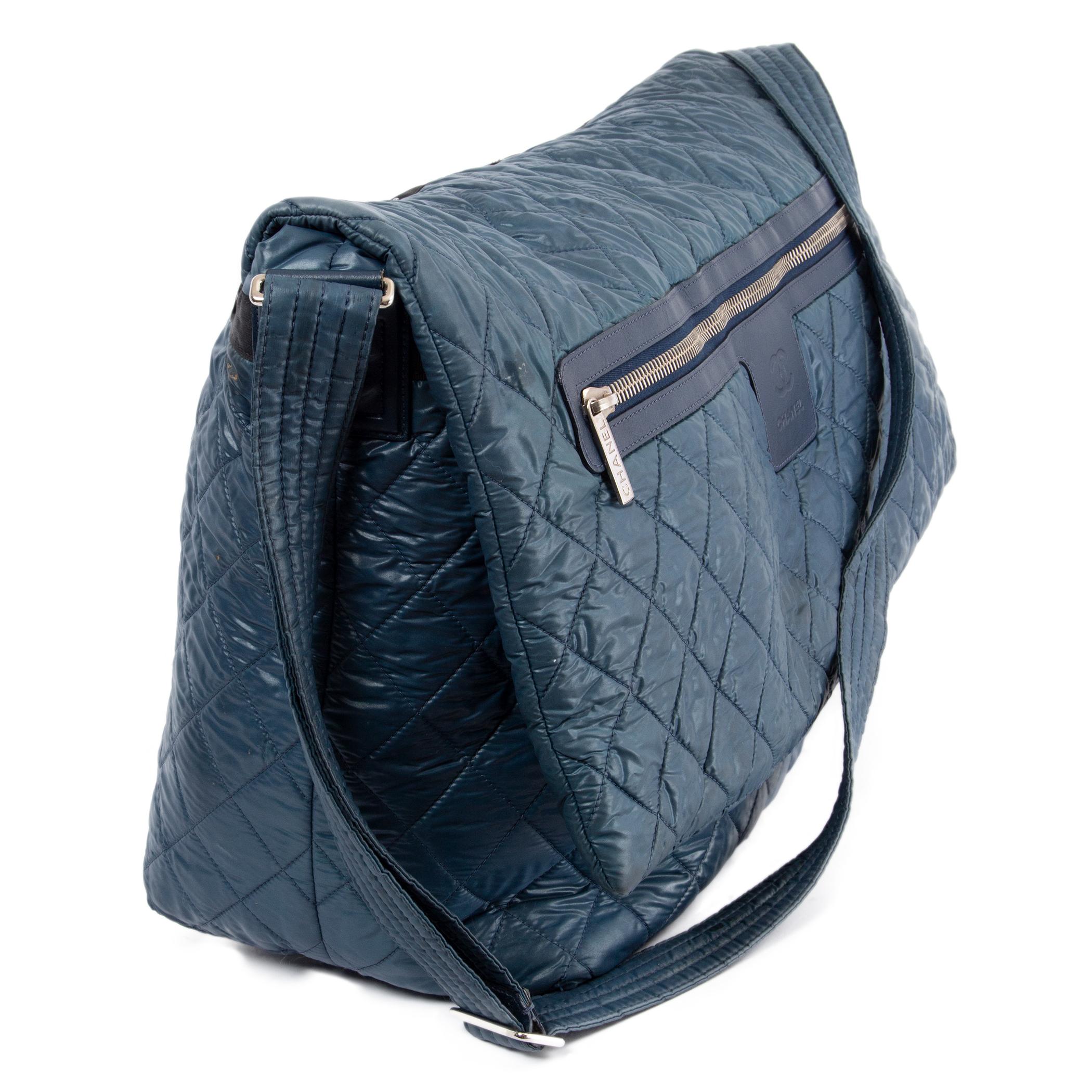 100% authentic Chanel Large Cocoon messenger bag in petrol blue nylon with leather trimming and silver-tone hardware. The design features a big zipper pocket at front and inside push-buttons. Opens with a flap to a black nylon interior. Has been