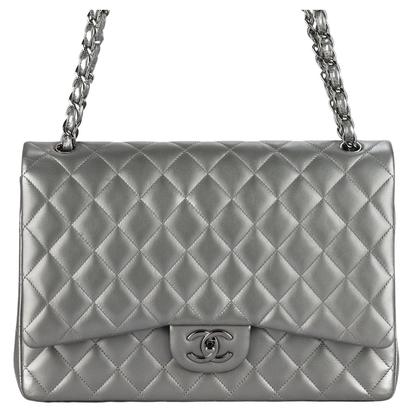 Questa Chanel in pelle d'agnello metallizzata trapuntata con doppia patta in grigio antracite. Questa borsa a tracolla è realizzata in pelle di agnello grigia trapuntata di diamanti. Gli spallacci sono in catena argentata infilata in pelle. La patta