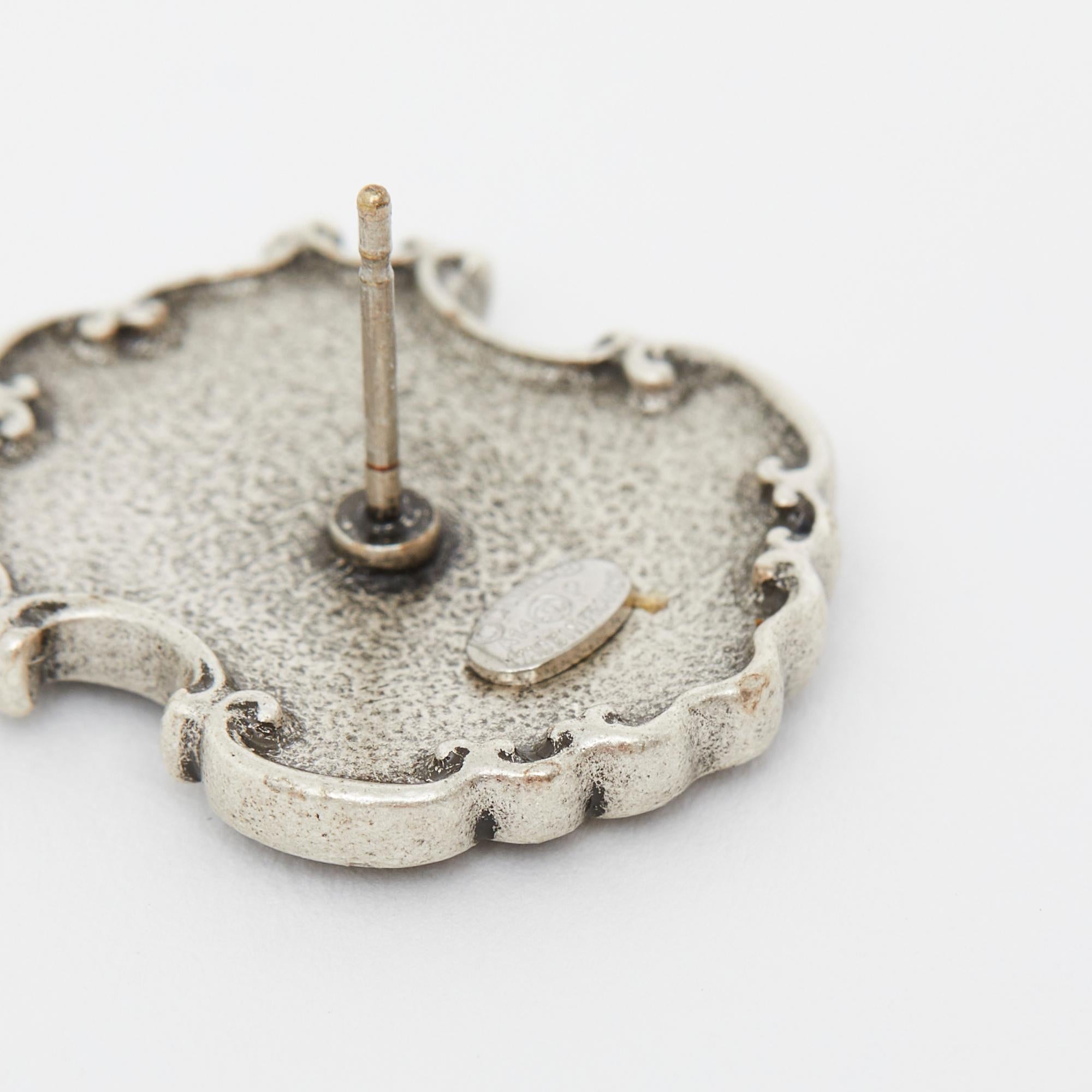 Chanel earrings from the Métiers d'Art Dallas or Pre Fall 2014 collection, silver-plated metal studs with a sheriff's coat of arms motif, from the Métiers d'Art Paris Dallas collection. Width 1.85 cm x height 2.2 cm. The earrings are delivered