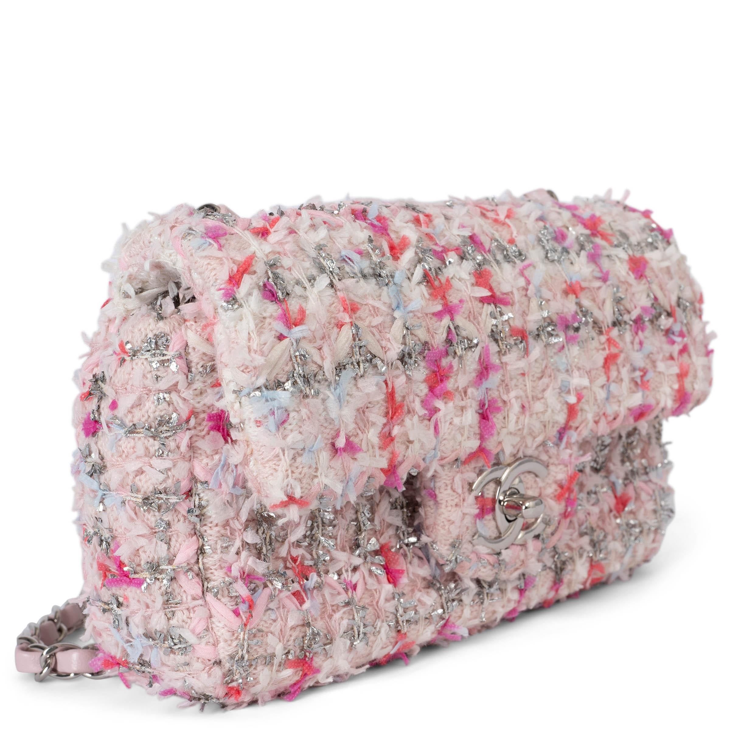 This 100% authentic Chanel Classic Mini flap bag is crafted from pale pink and silver lurex knit tweed with ribbon detailing in fuchsia, coral, and white. It features a silver-tone double chain strap interlaced with pale pink leather and an open