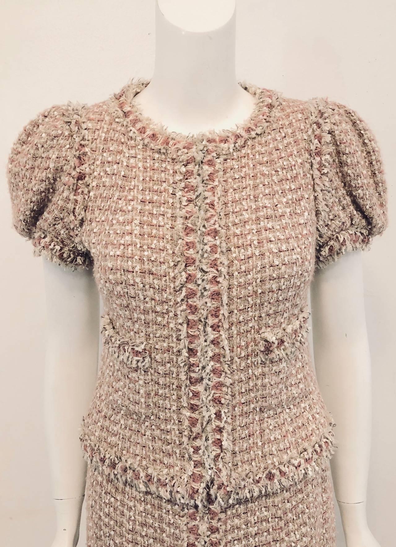 This Chanel skirt suit with short poof sleeves contains a splatter of white mini sequins throughout. Jacket is fully lined with pink Camellia print silk jacquard.  Skirt is lined in plain silk. Jacket features two patch pockets.  One pocket is