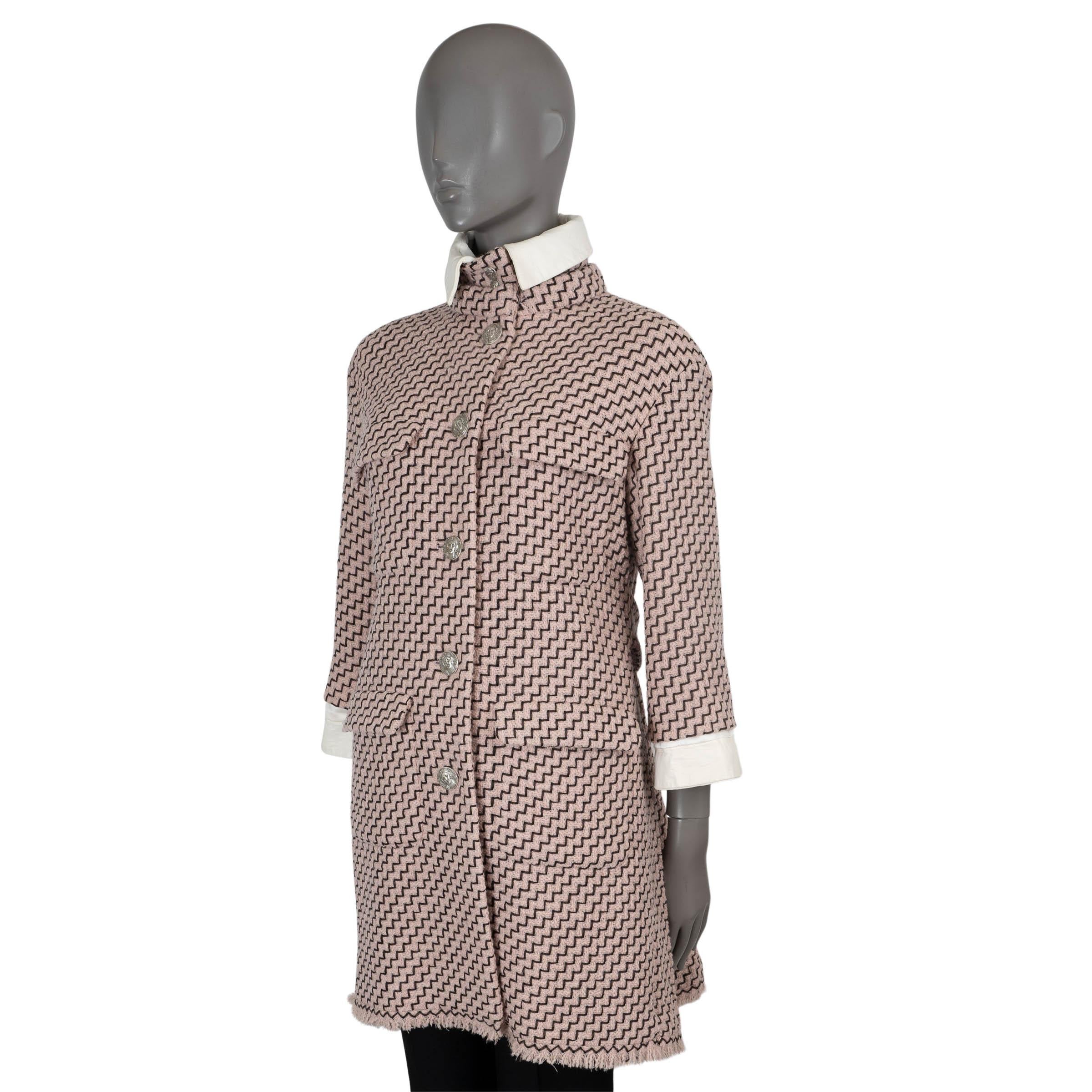 100% authentic Chanel zigzag tweed coat in pale pink and black wool (91%) and nylon (9%). Features four flap pockets on the front, a high-neck with tie, 3/4 sleeves with cream lambskin cuffs, pleated back with belt and fringed bottom hem. Closes