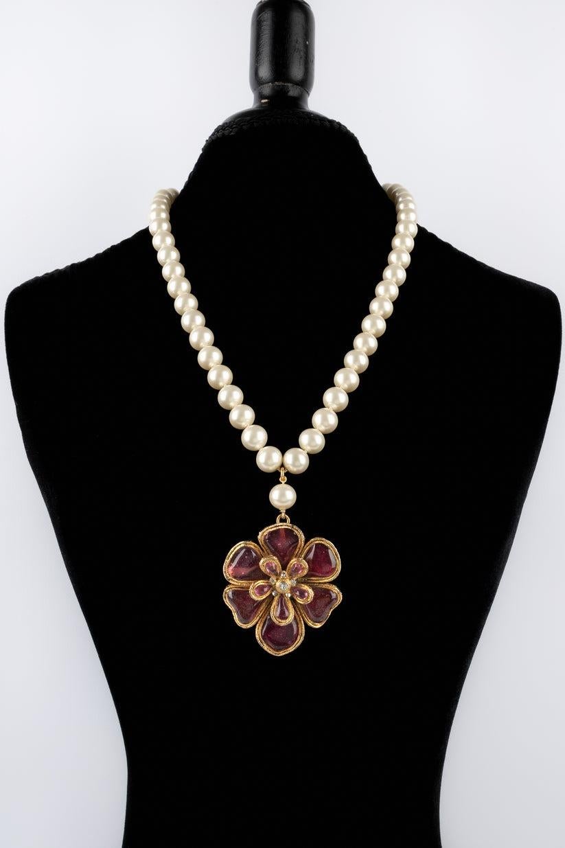 Chanel - Costume pearl necklace ornamented with a golden metal and pink glass paste pendant brooch.

Additional information:
Condition: Very good condition
Dimensions: Length: 66 cm

Seller Reference: CB20
