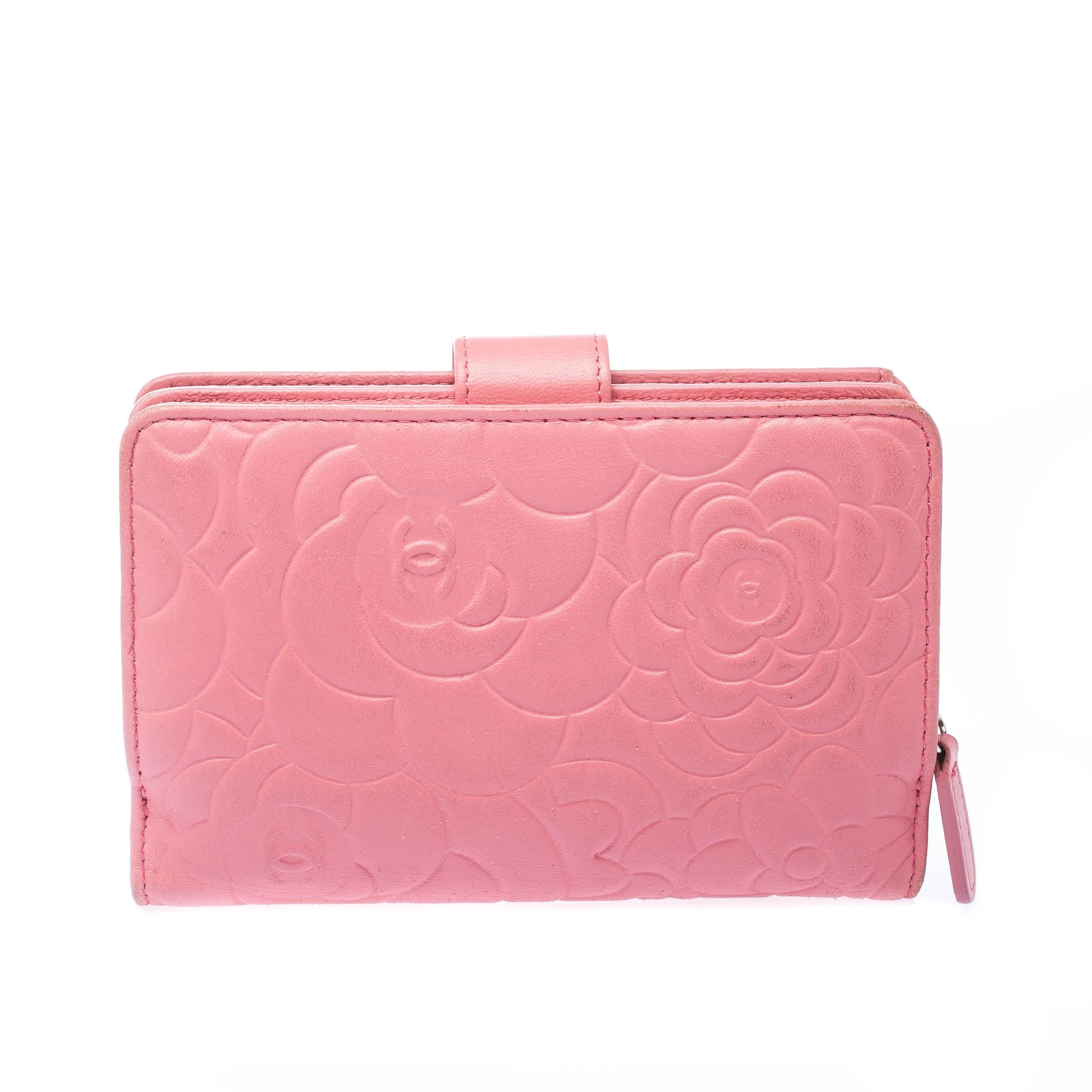 Embossed with the signature Camellia design, this Chanel wallet will keep you stylish and organised. Its bright pink color is matched with a smooth texture and a silver-tone metal CC charm on the front of the flap. The snap closure opens up to a