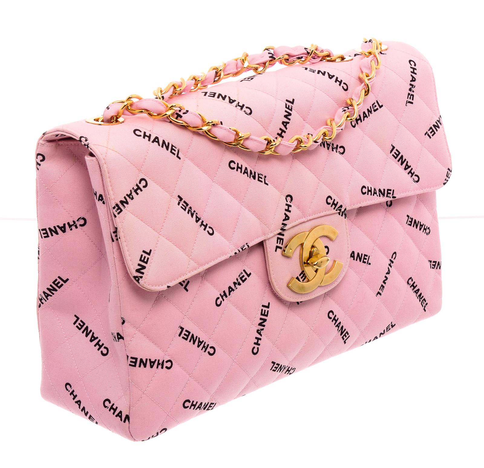 Pink canvas Chanel Logo Jumbo XL Maxi Single Flap Bag with gold-tone hardware, convertible chain-link shoulder strap, single patch pocket at exterior back, tonal leather interior lining, dual pockets at interior walls; one with zip closure and CC