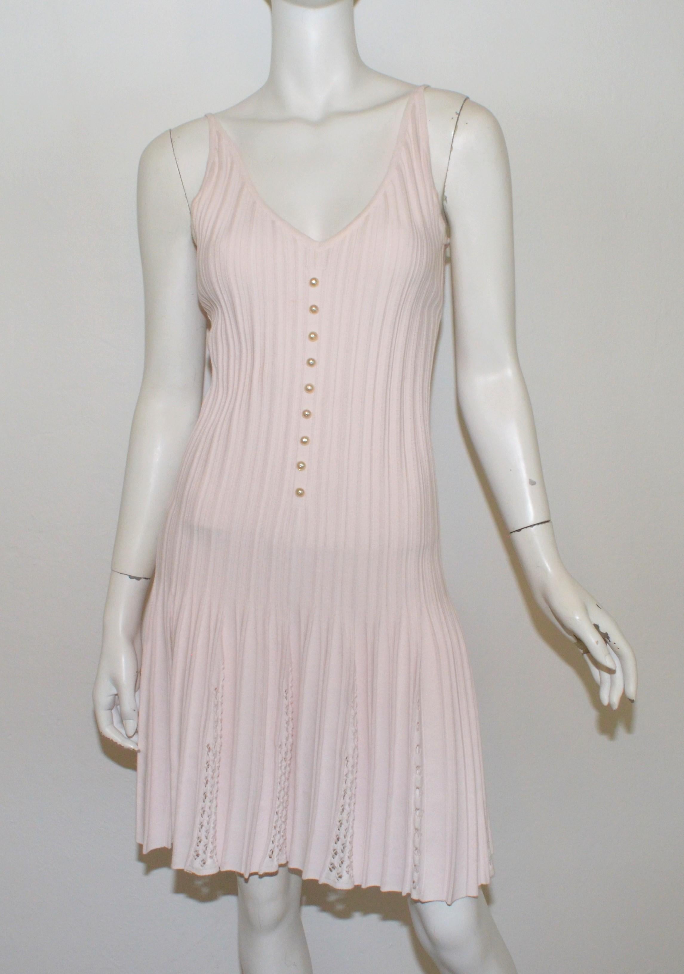Chanel pink knit fit and flare dress featured decorative pearl buttons along the front, V-backline, and a cutout knit design to the skirt. Size 38, made in France.

Measurements: bust 28”, waist 26”, hips 35”, length 27” (knit fabric has some