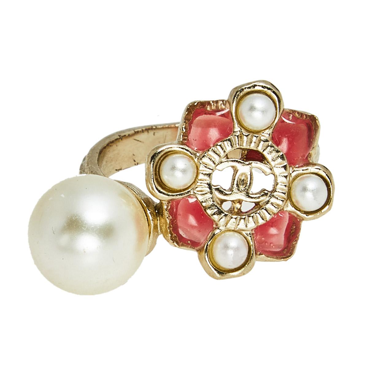 Chanel's cocktail ring brings a statement size and look. It is made of gold-tone metal and the front is adorned with resin, pearls, and the CC logo. Wear it solo for an evening look.