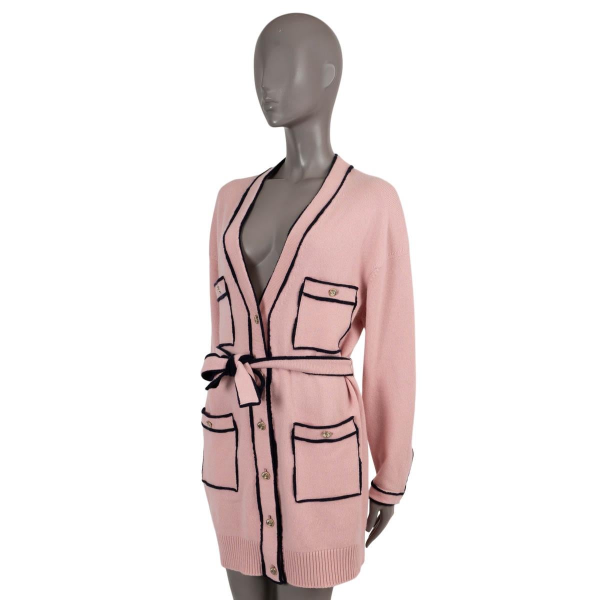100% authentic Chanel cardigan knit dress in light pink cashmere (100%) with navy blue trims. Features a V-neck, four buttoned flap pockets, rib-knit hem and matching self-tie belt. Opens with No 5 buttons on the front and is unlined. Has been worn