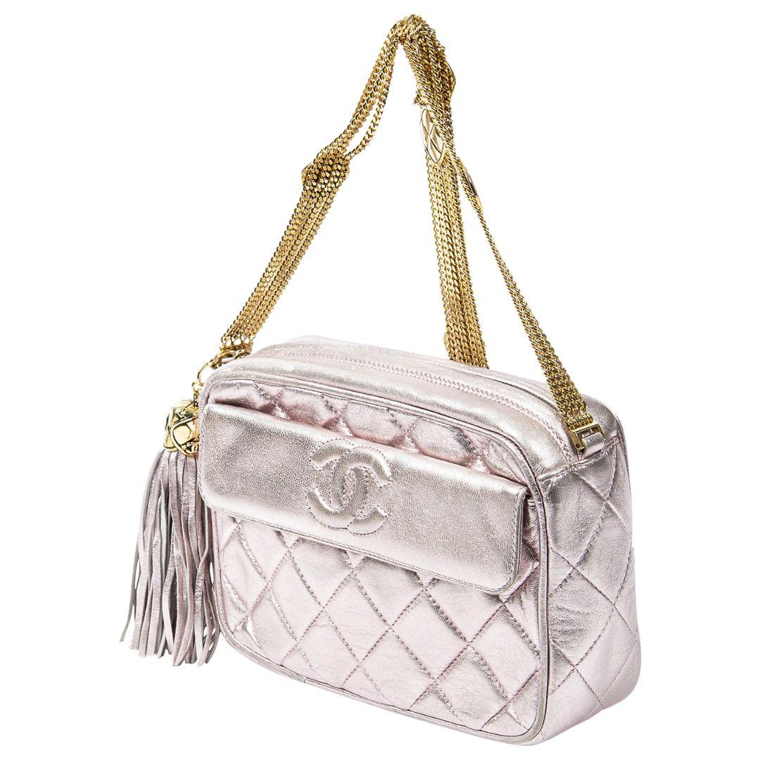 Add a pop of color to your ensemble with this pink quilted lambskin leather small tassel chain camera bag. The vibrant pink quilted lambskin leather is paired with a gold chain strap for a striking combination. The bag features a zipper closure and
