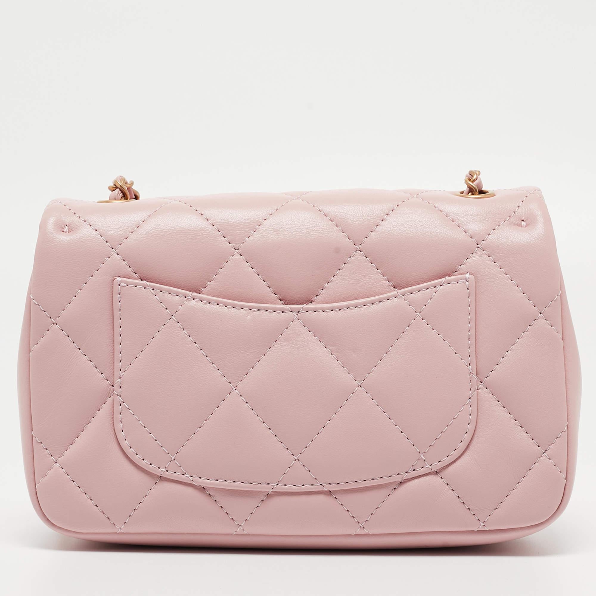 The Chanel classic flap bag is an exquisite blend of timeless elegance and modern charm. Crafted from luxurious quilted leather in a delicate pink hue, it features a miniature heart charm for a playful touch. This compact classic flap bag epitomizes