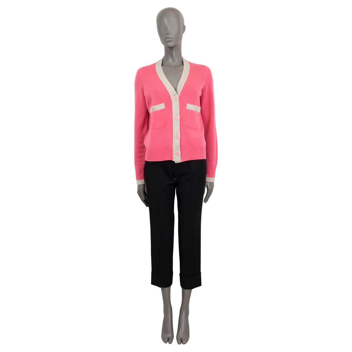 100% authentische Chanel Strickjacke aus rosa Kaschmir (100%) mit kontrastierendem sandfarbenem Saum. Mit zwei aufgesetzten Taschen auf der Vorderseite, rosa geblümten Knöpfen und einem Gürtel zum Binden auf der Rückseite. Wurde getragen und ist in