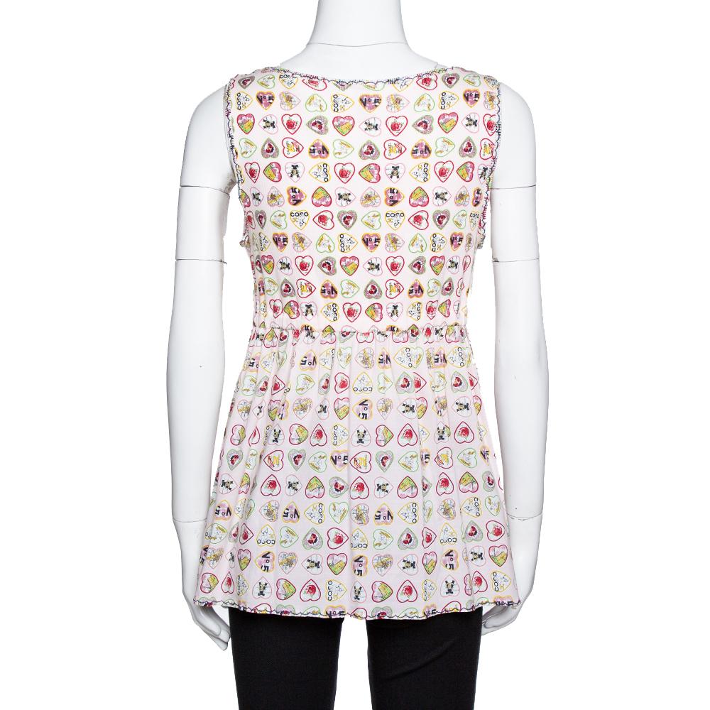 How lovely does this Chanel top look! The pink sleeveless creation is made of a cotton blend and features a valentine inspired print all over. It has been styled with a plunging V-neckline and a tie-up at the waist. Pair it with dark-hued pants and