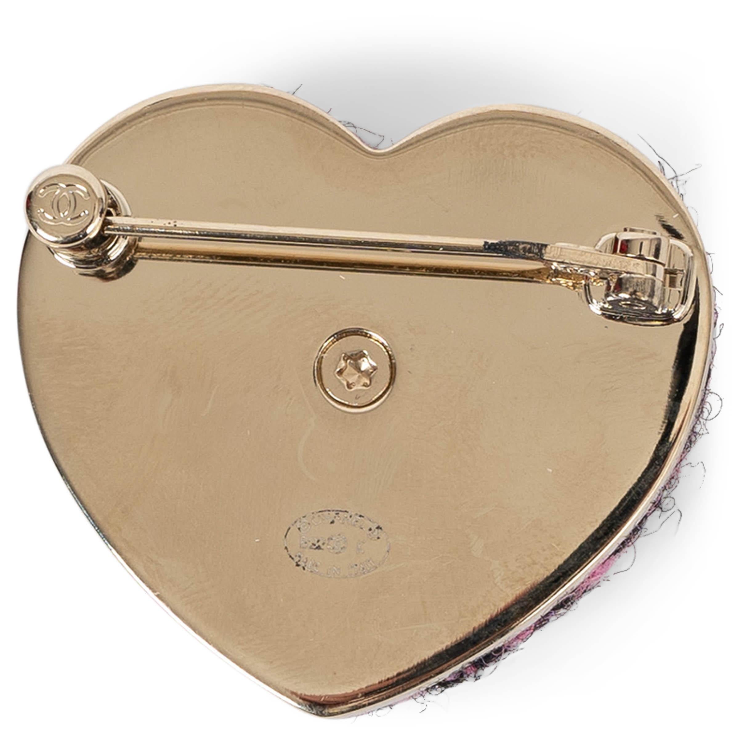 This 100% authentic Chanel brooch in black and pink tweed is a charming expression of the house’s timeless elegance. Designed in a heart shape, it features a gold-tone metal CC at the center, adding a signature touch. A playful yet sophisticated