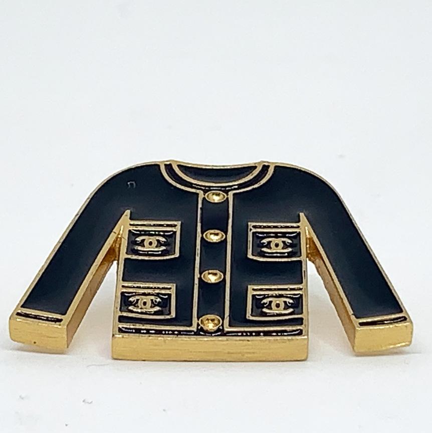The pin's is from Maison CHANEL. It represents the little black jacket revisited, the iconic and timeless jacket of the House, here in black enamel, and on the lapels in metal gilded with fine gold. 
The pin is in very good condition because it has