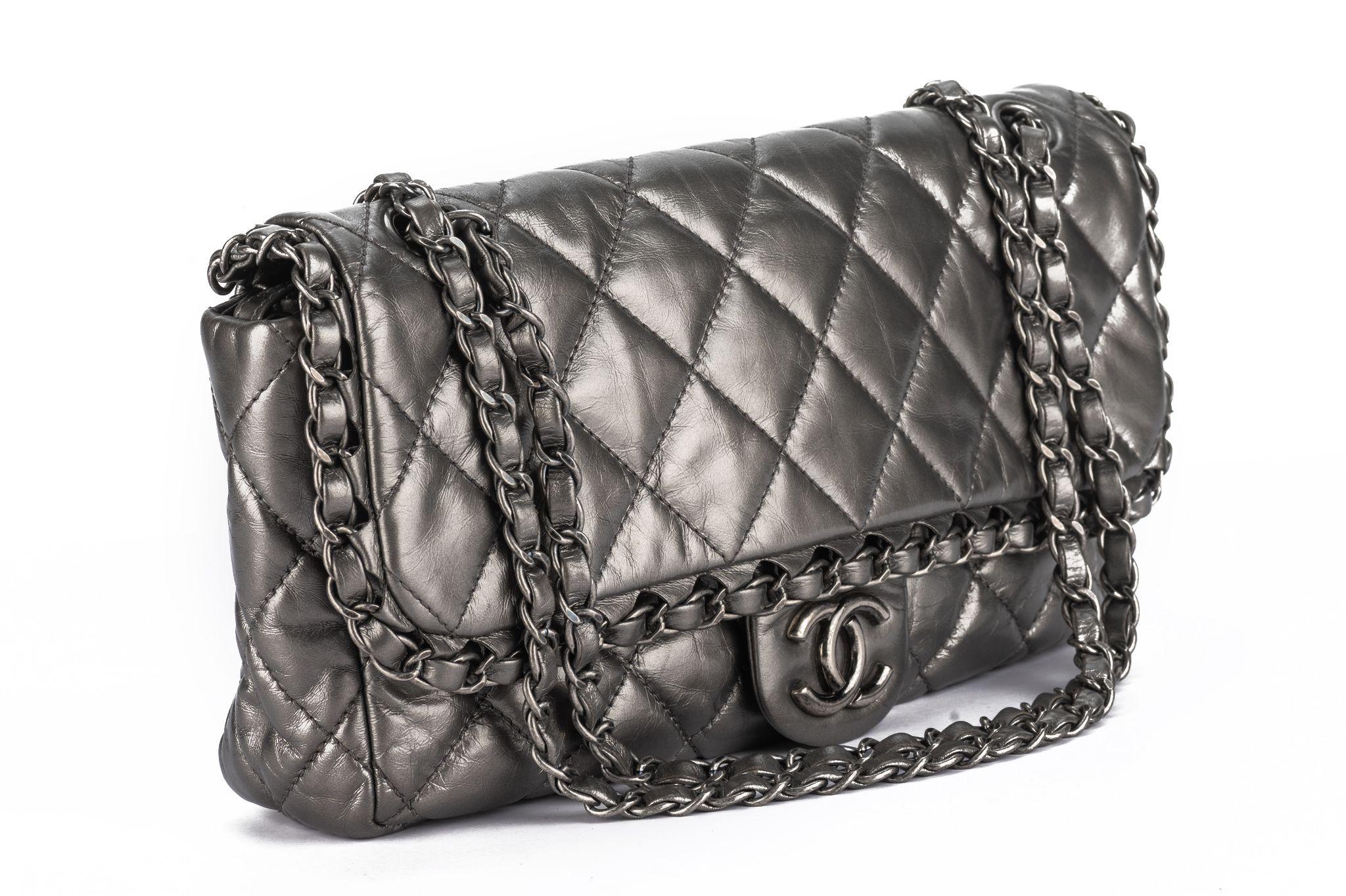 Chanel Chain Me Flap Bag in quilted matte gray metallic calfskin leather and matte gunmetal hardware details. Features a woven chain and the CC logo. Bag closes with magnetic button and has a sliding chain strap for shoulder or crossbody wear. Comes