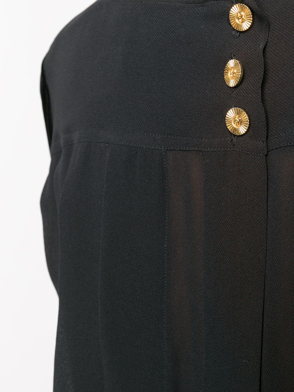 Expertly crafted in France from fluid black silk, this pre-owned black top from Chanel features long-sleeves, a round-neck collar and a straight hem design. The lateral pleated detailing at the front, gold-tone button fastening at the rear and