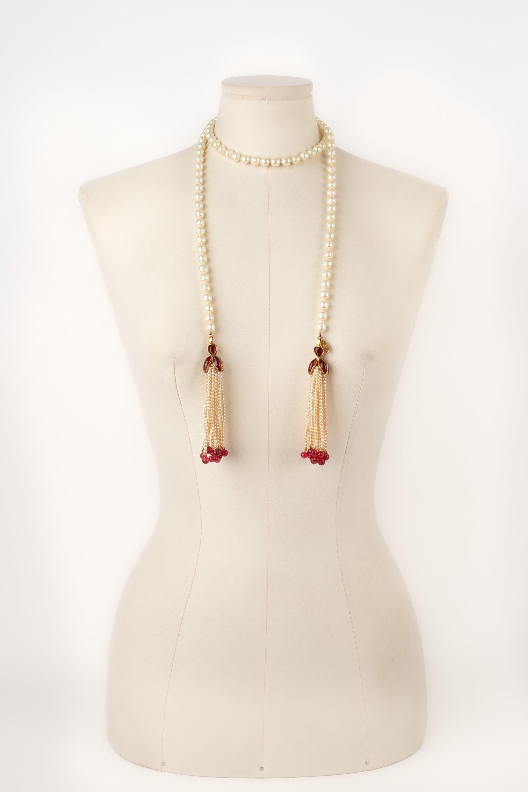Chanel - (Made in France) Costume pearl necklace assembled with knots and ending with glass paste and pearl pompoms. 1983 Collection.
 
 Additional information: 
 Condition: Very good condition
 Dimensions: Length with the pompoms: 120 cm
 Period: