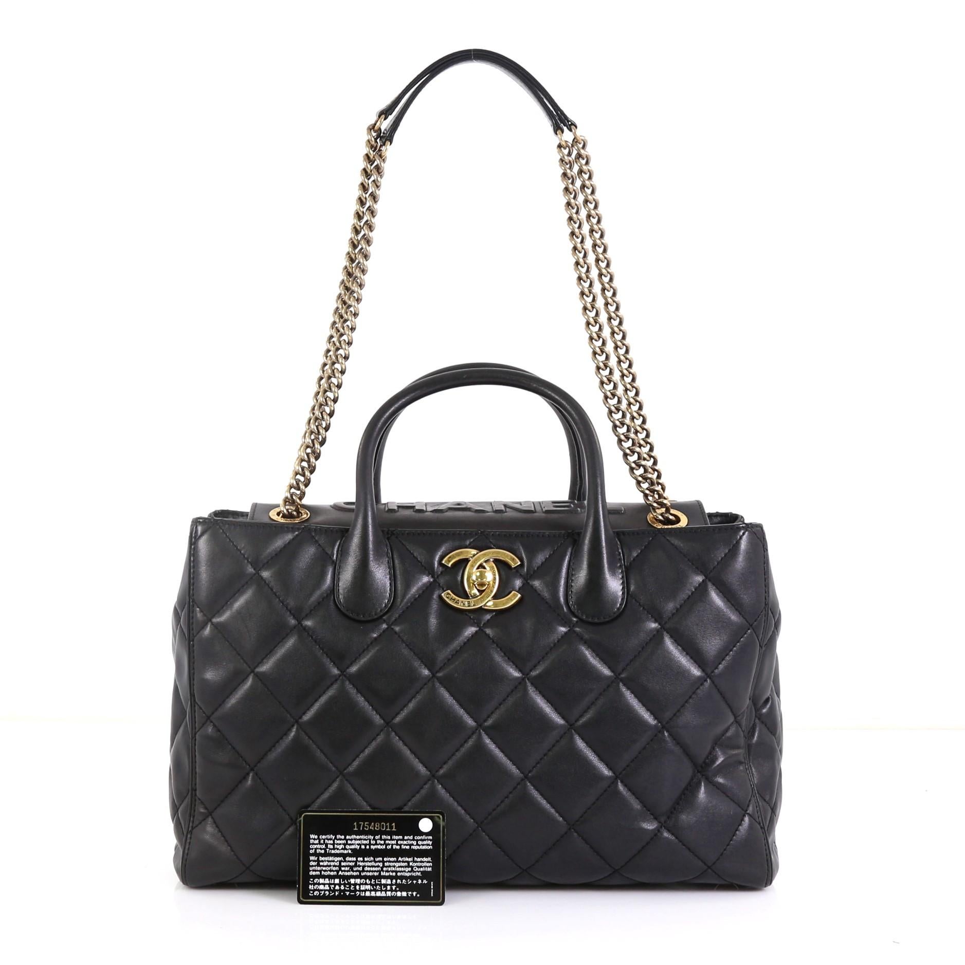 This Chanel Portobello Logo Tote Quilted Lambskin Medium, crafted from black quilted lambskin leather, features dual rolled handles, chain strap with leather pad, and aged gold-tone hardware. Its CC turn-lock closure opens to a gold leather interior