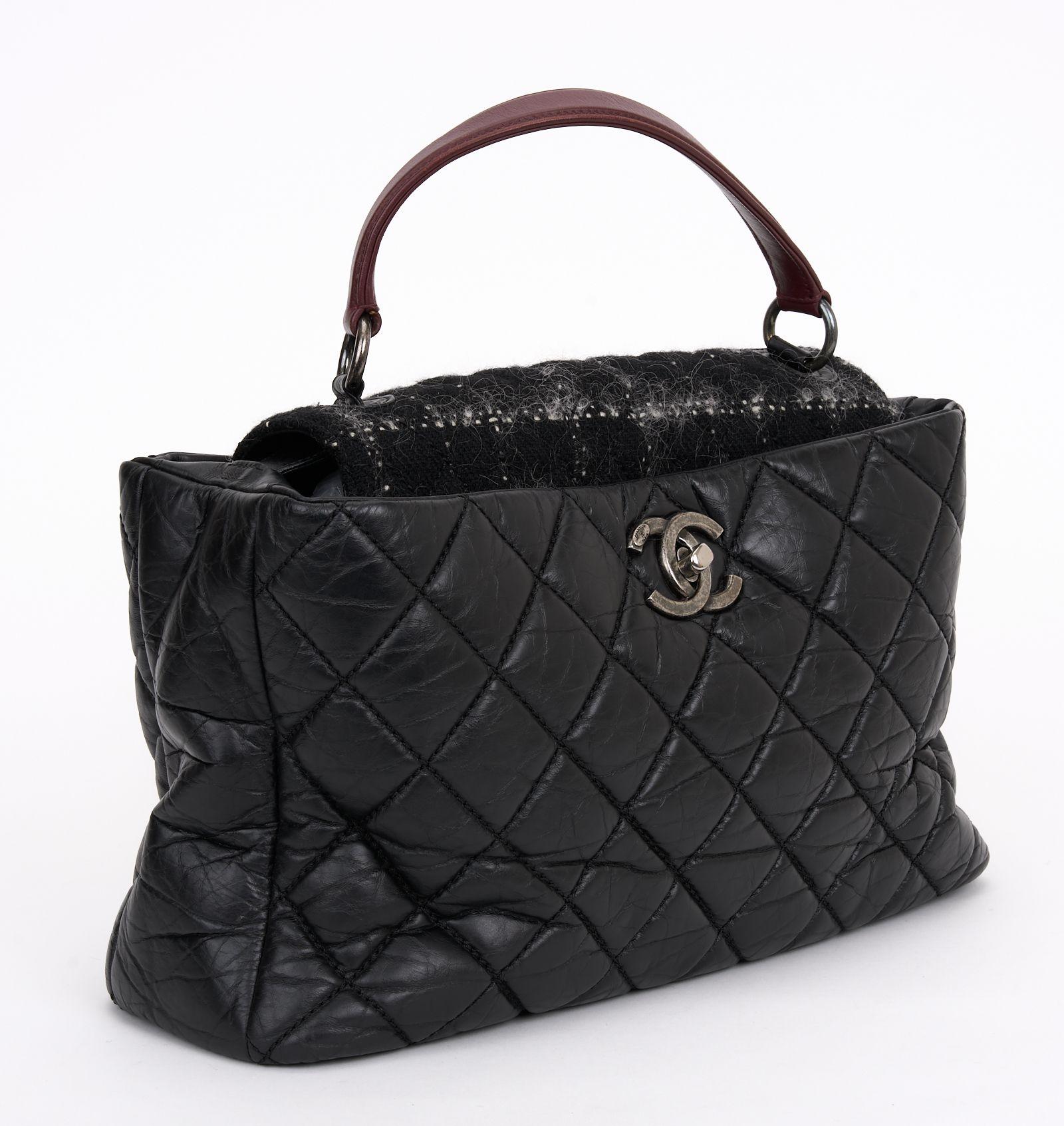 This Chanel Portobello Quilted Aged Calfskin and Tweed bag features black quilted aged calfskin leather and tweed, a flat leather top handle and aged silver-tone hardware. Its CC turn-lock closure opens to a red fabric interior. Comes with hologram