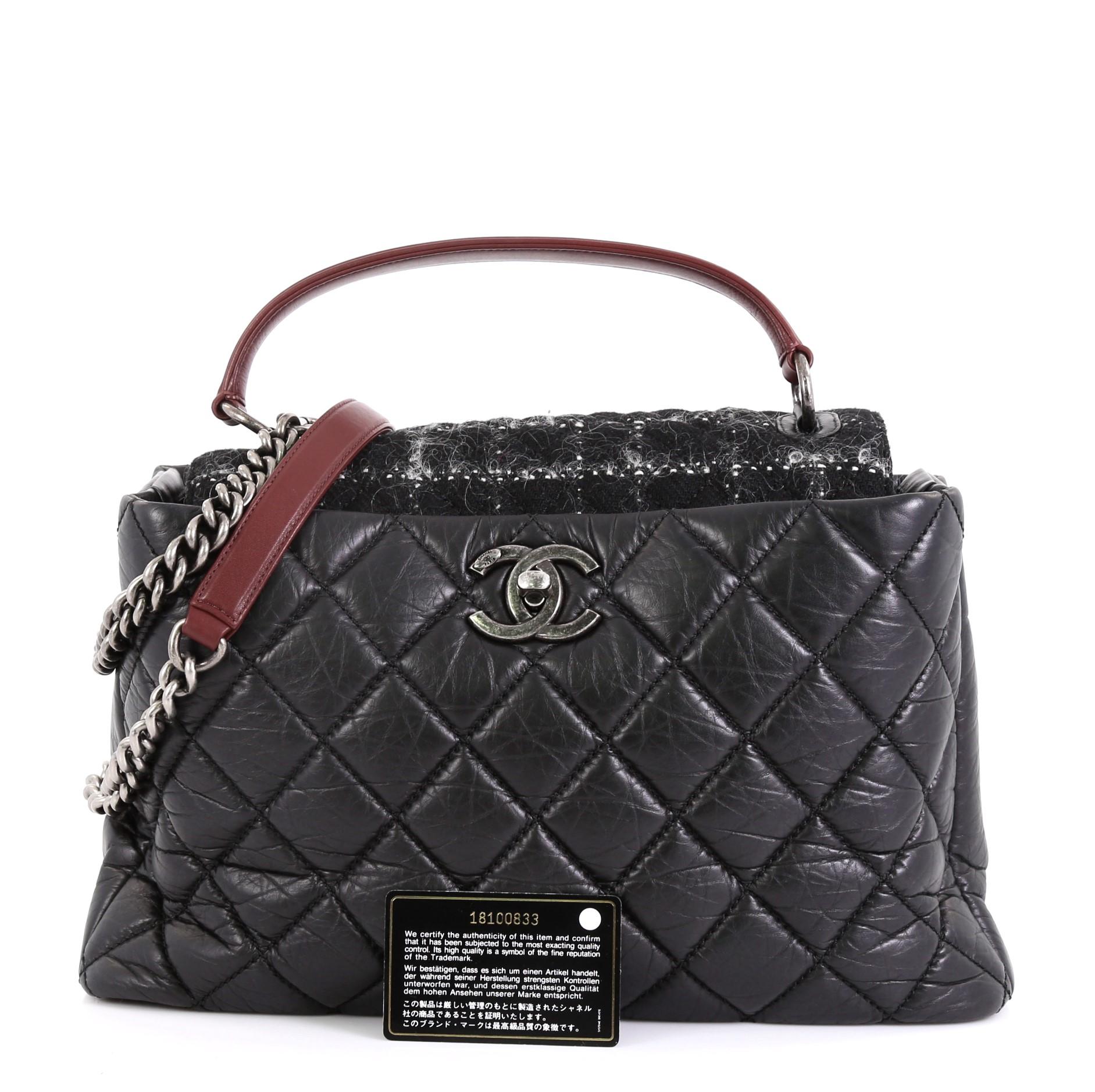 This Chanel Portobello Top Handle Bag Quilted Aged Calfskin and Tweed Large, crafted from black quilted aged calfskin leather and tweed, features flat leather top handle and aged silver-tone hardware. Its CC turn-lock closure opens to a red fabric