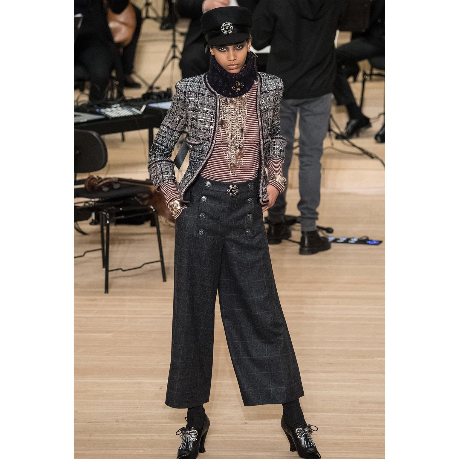 These are new with original tags Chanel Pre-Fall 2018 charcoal grey wool trousers with windowpane blue grid lines throughout. The front of the pants have a sailor style button panel that conceals the front zipper opening and a hook and eye closure.