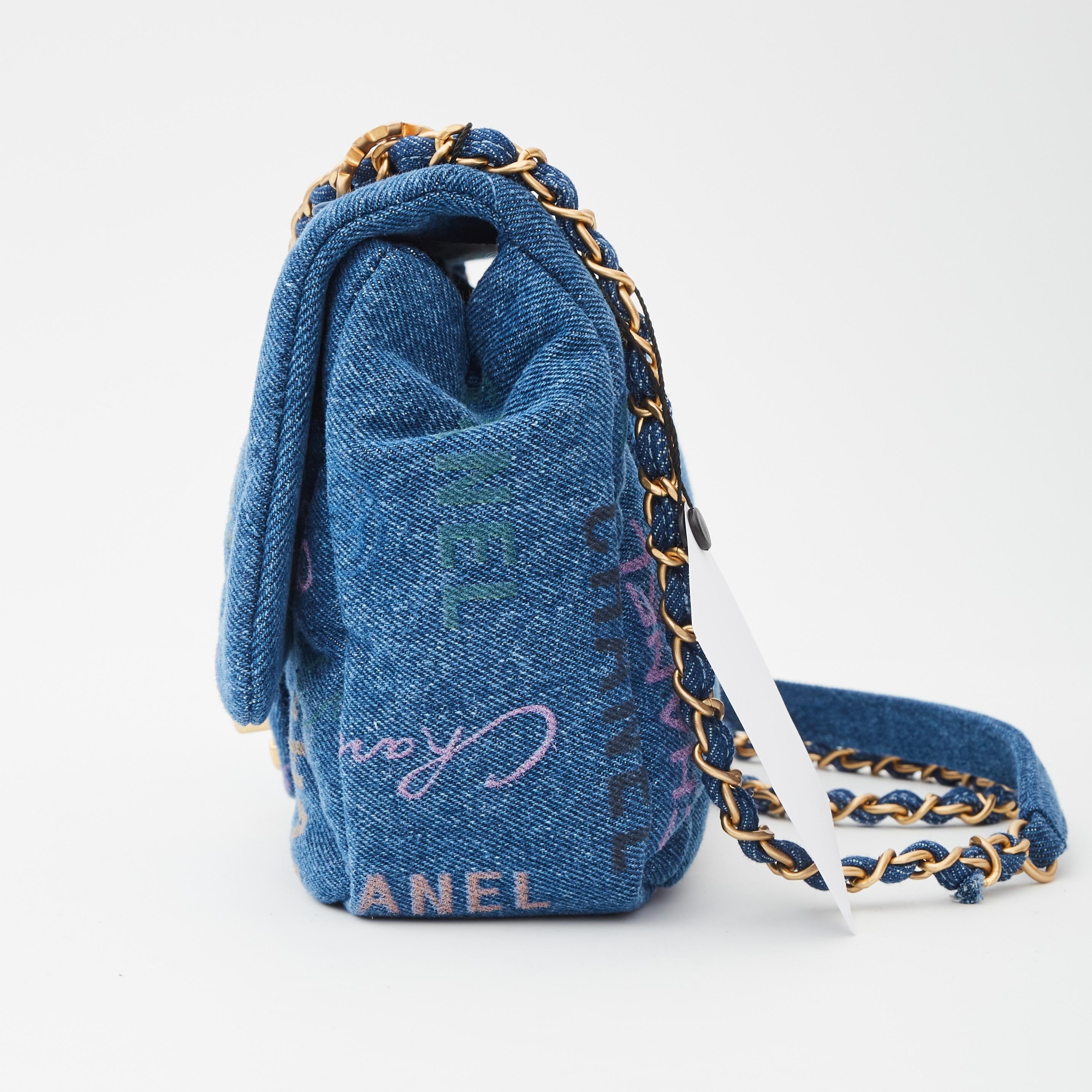Questa borsa con patta è realizzata in denim blu. La borsa è dotata di una tracolla crossbody in tela con catena d'oro invecchiata. Presenta inoltre un motivo CC a graffiti e un lucchetto Chanel CC color oro invecchiato che apre la patta per