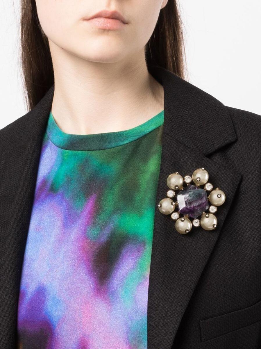 A stone of protection, purple fluorite is said to radiate energy throughout the body, relieving stress, spiritual discomfort, and physical blockages. Designed in 1997, this pre-owned vintage Chanel brooch features a large central fluorite stone