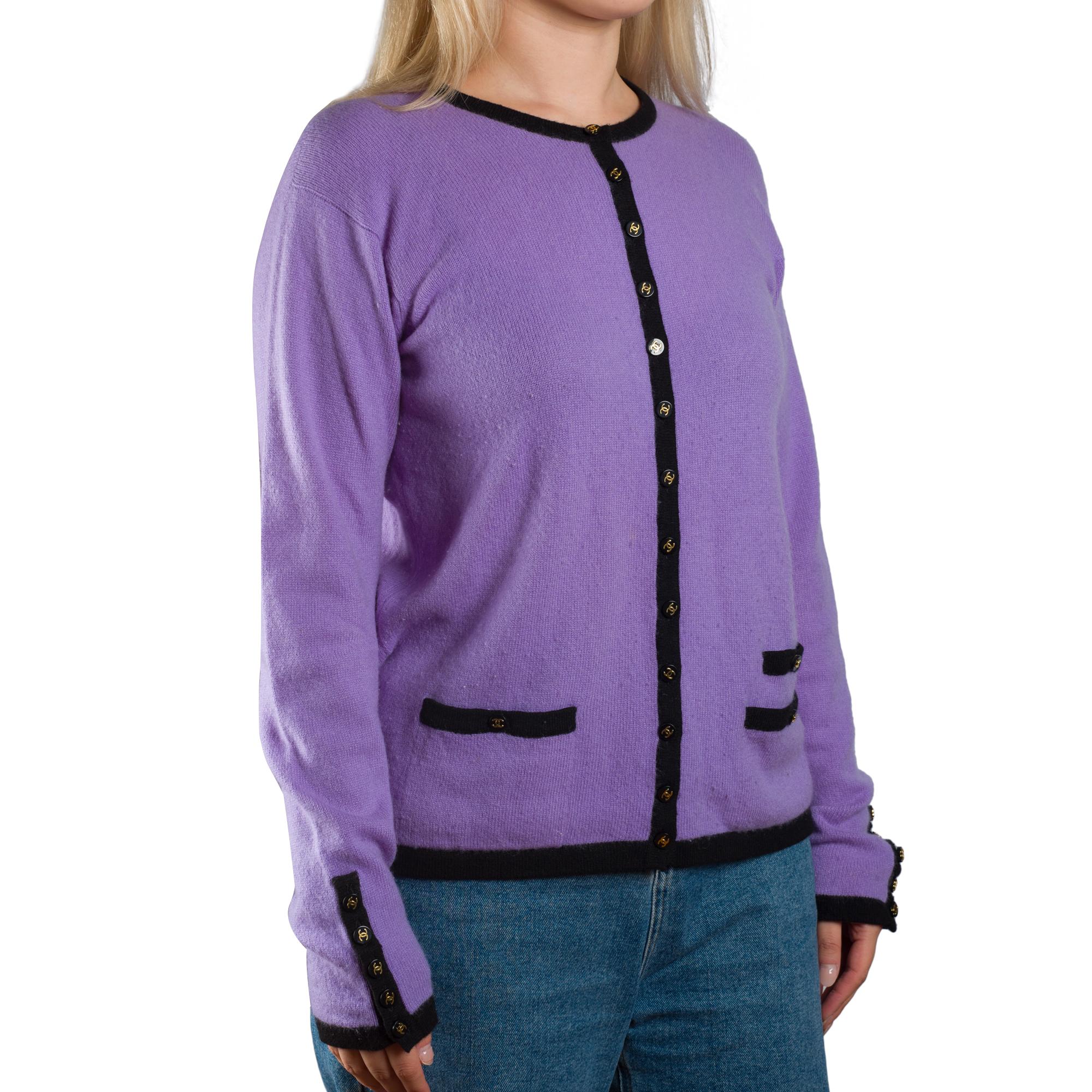 Diese lilafarbene Strickjacke von Chanel aus Kaschmir hat schwarze Besätze, goldfarbene CC-Logoknöpfe und zwei dekorative Taschenklappen. Das leuchtende Violett bildet einen eleganten Kontrast zu den schwarzen Akzenten

MATERIAL: Kaschmir
Größe: