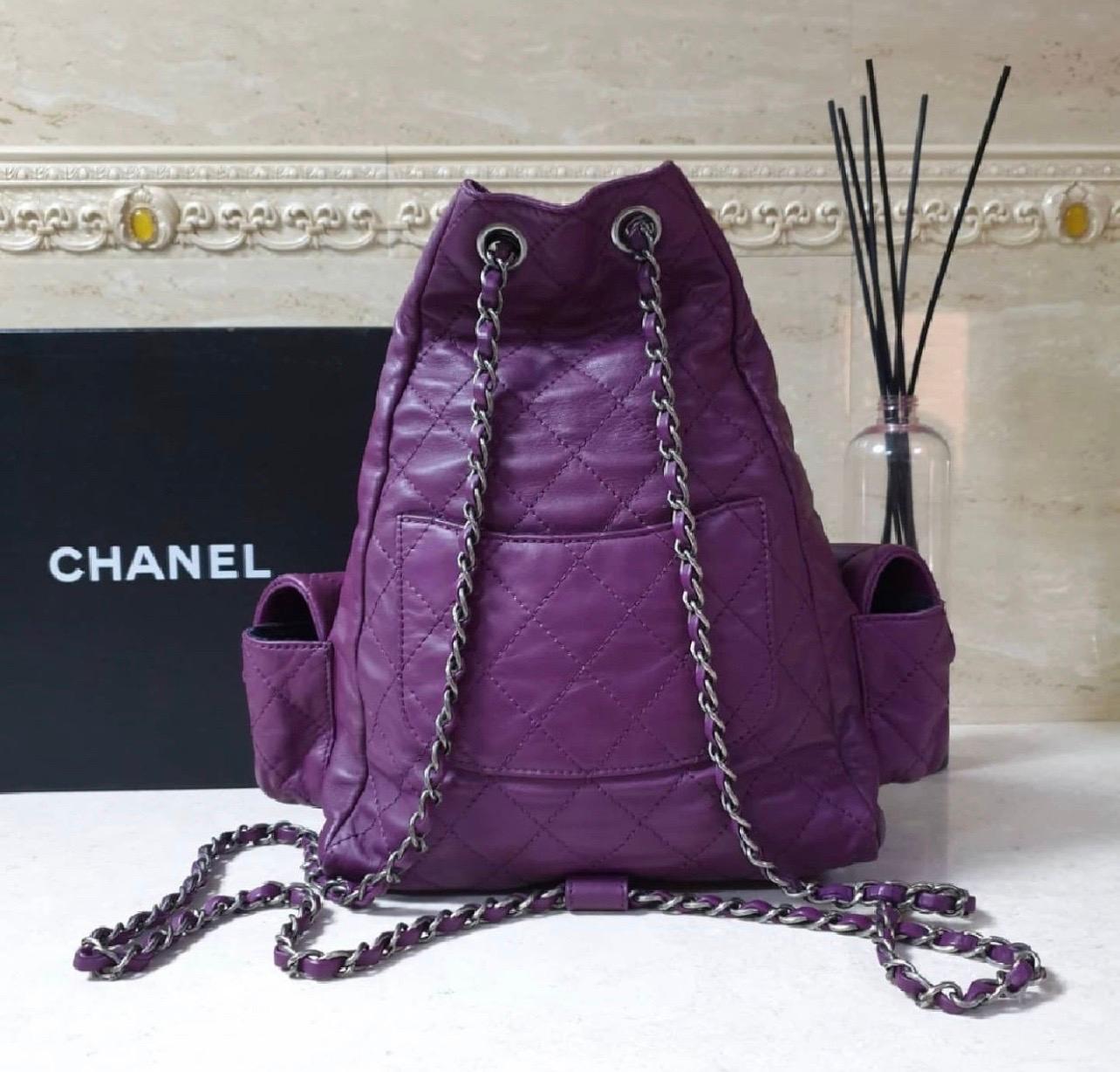 Chanel Purple Lambskin Large Backpack Is Back Bag is a true gem! 
This bag is crafted of soft lambskin leather in purple, while the side flap pockets and base features quintessential diamond quilting. 
This fantastic backpack has aged ruthenium