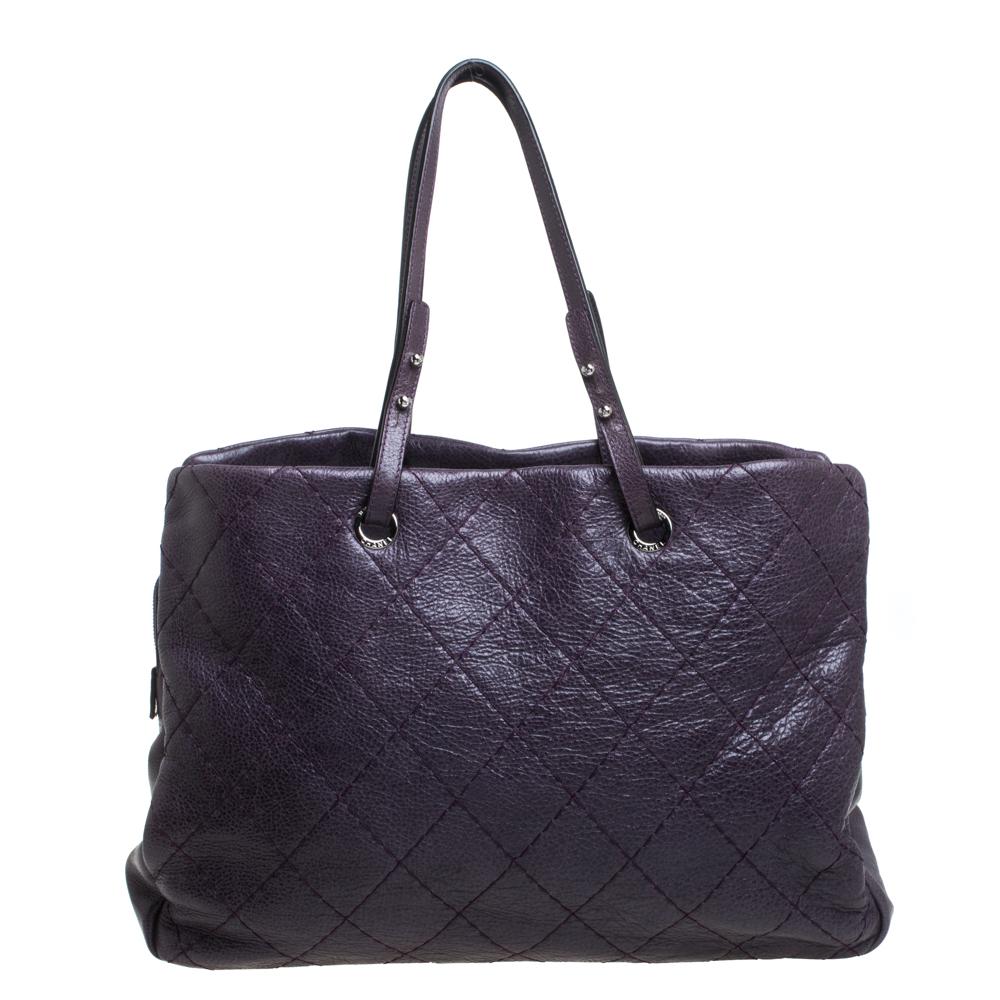Brilliantly designed to assist you with all your daily needs, this stylish Chanel tote is crafted from quilted leather in a purple shade. It features three spacious compartments for easy organization and is secured by zip fastening. The bag suspends