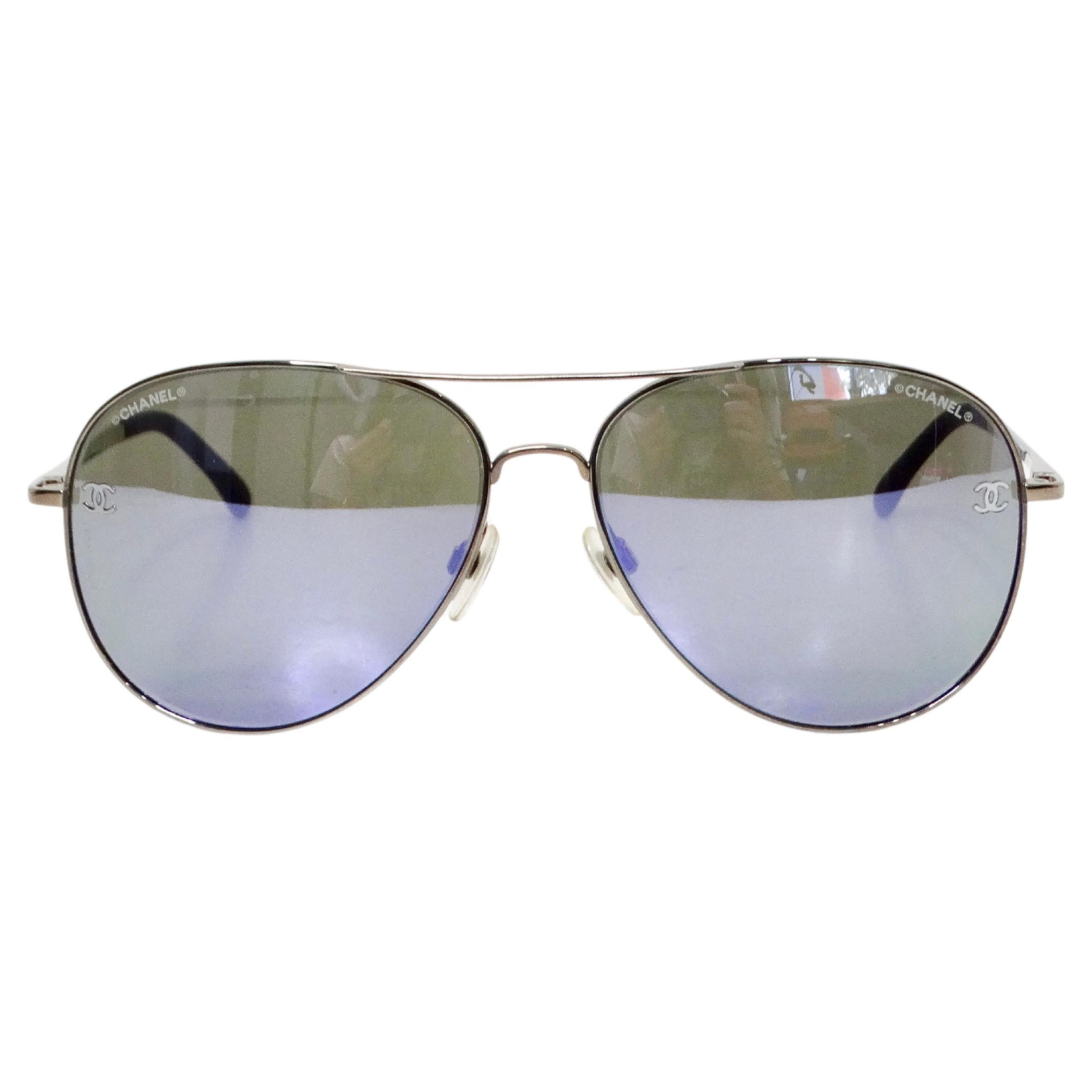 The Chanel  Purple & Silver-Tone Metal Frame Pilot Aviator Sunglasses are the epitome of luxury and style. Featuring a sleek silver-tone metal frame, these sunglasses exude modern sophistication, while the purple accents at the ends add a vibrant,