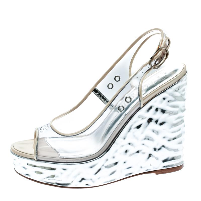 Contemporary and edgy, these metallic silver sandals from Chanel are perfect to elevate your style quotient! They have been crafted from PVC and patent leather trims and styled with peep-toes and buckled slingbacks. They are complete with