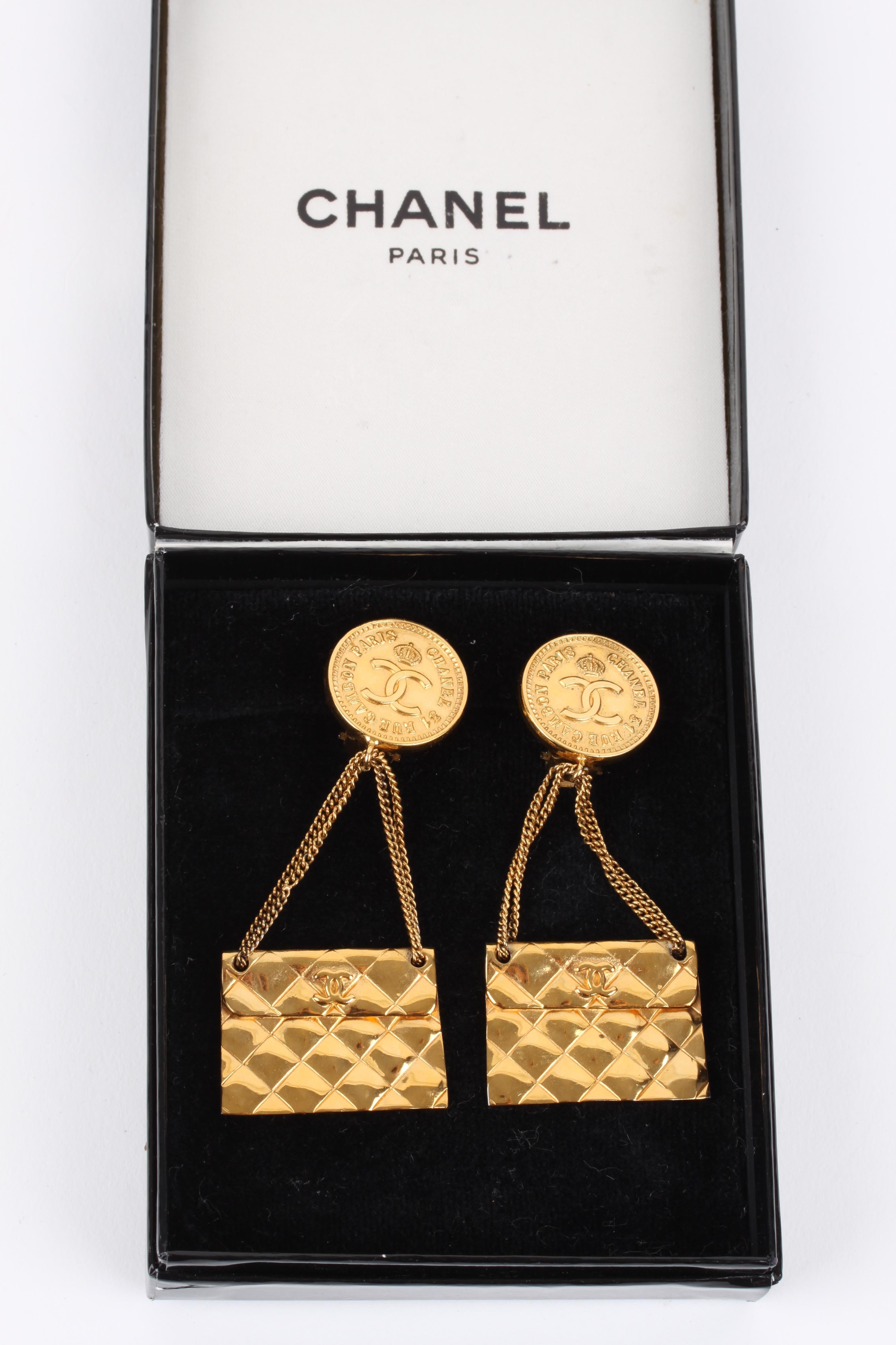 Spice up your outfit with these vintage Chanel clip earrings crafted from gold-tone metal.

On top a round coin with an interlocking CC logo in the center, a quilted 2.55 flap bag charm is dangling underneath on a thin chain.

Total length of these