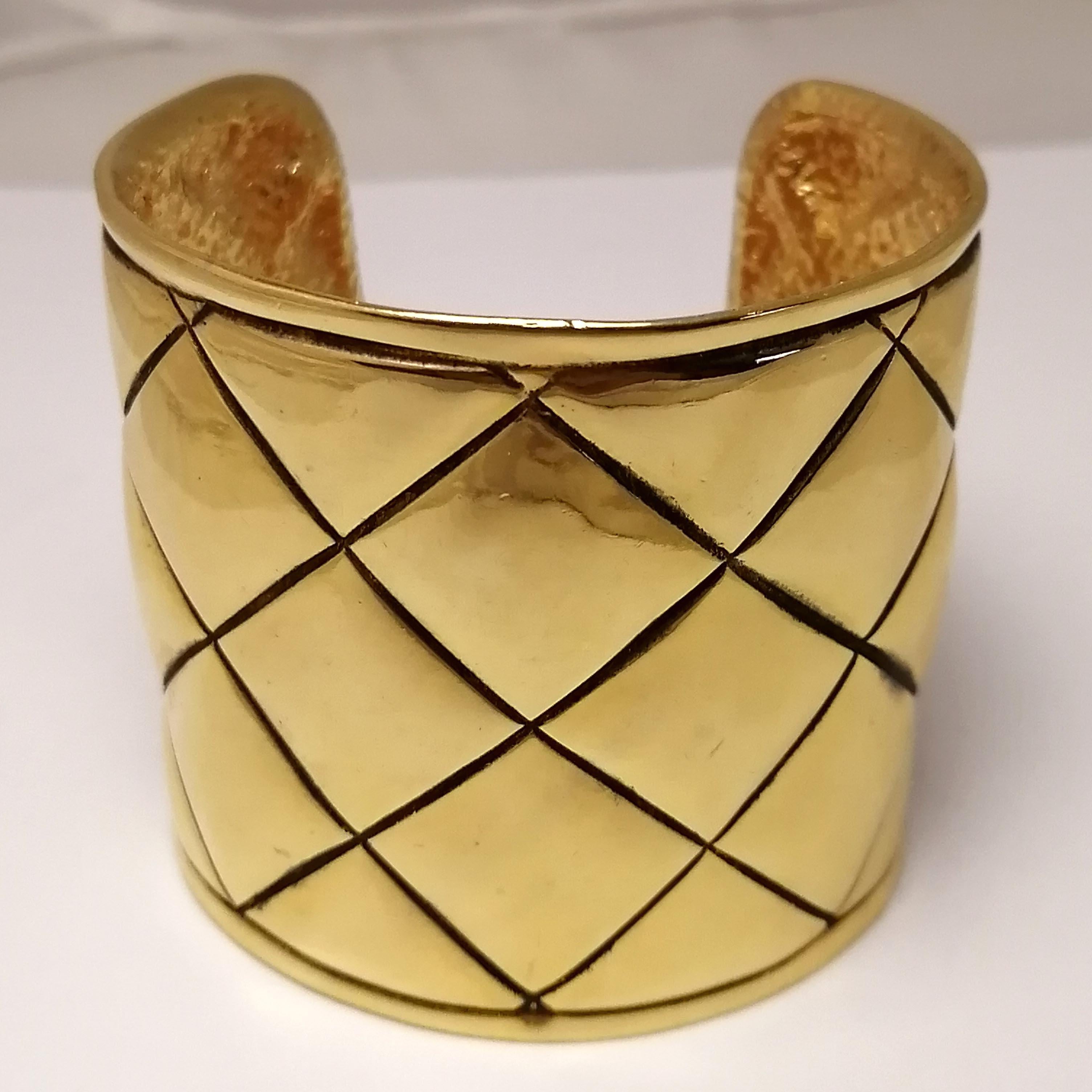 A 1980s French classic gilt metal bangle bracelet by Chanel. The rigid quilted design shows the CC logo on one of its sides and the brand's seal on the interior. It shows very mild marks of use.

Total dimensions: 6.3 x 6.8 x 5.8 cm. (2.5 x 2.63 x