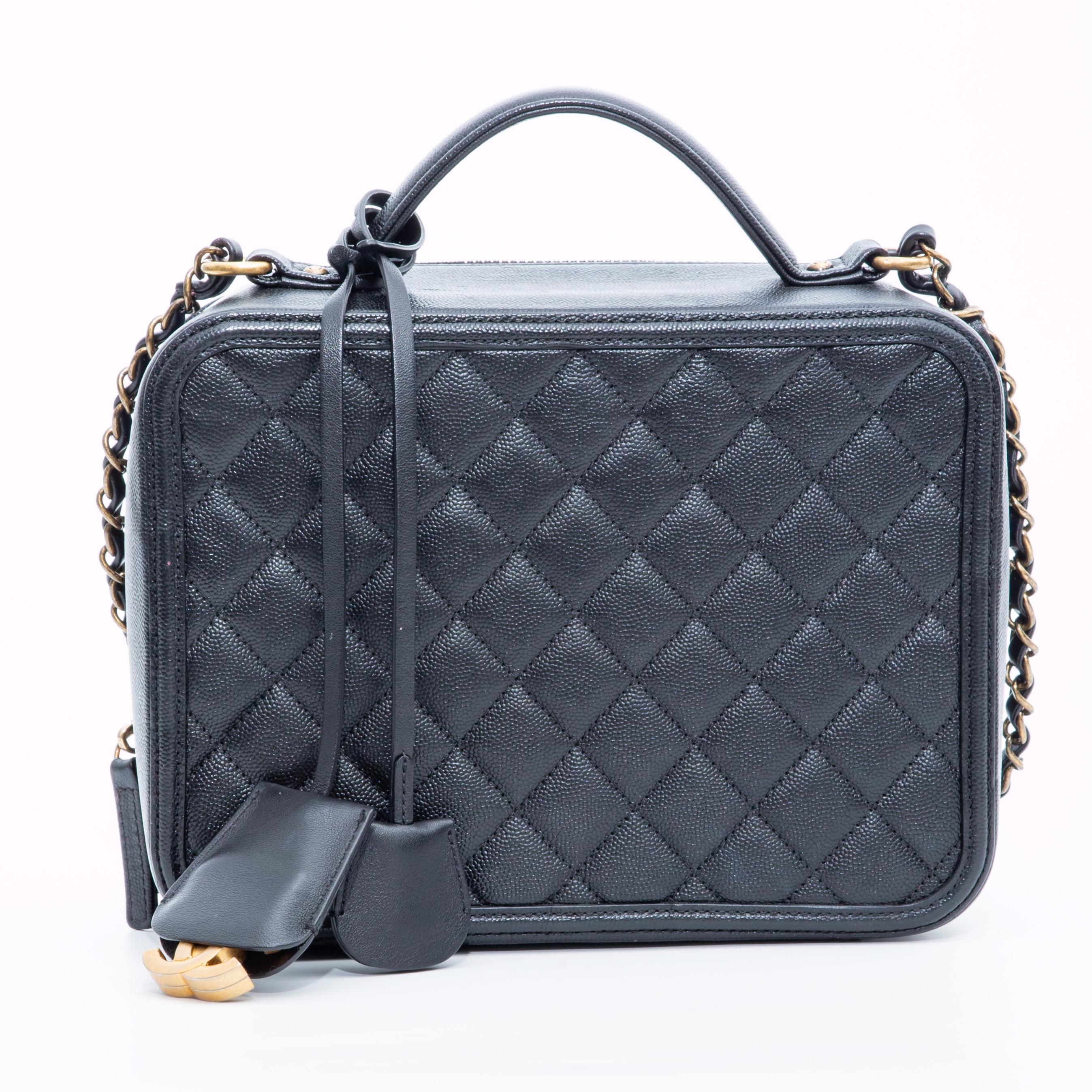 This Chanel CC Filigree Vanity Case is made with diamond quilted caviar leather in black. The bag features gold toned hardware, an embroidered CC at the front face, a gold toned chain interlaced with leather, a single flat leather top handle, and